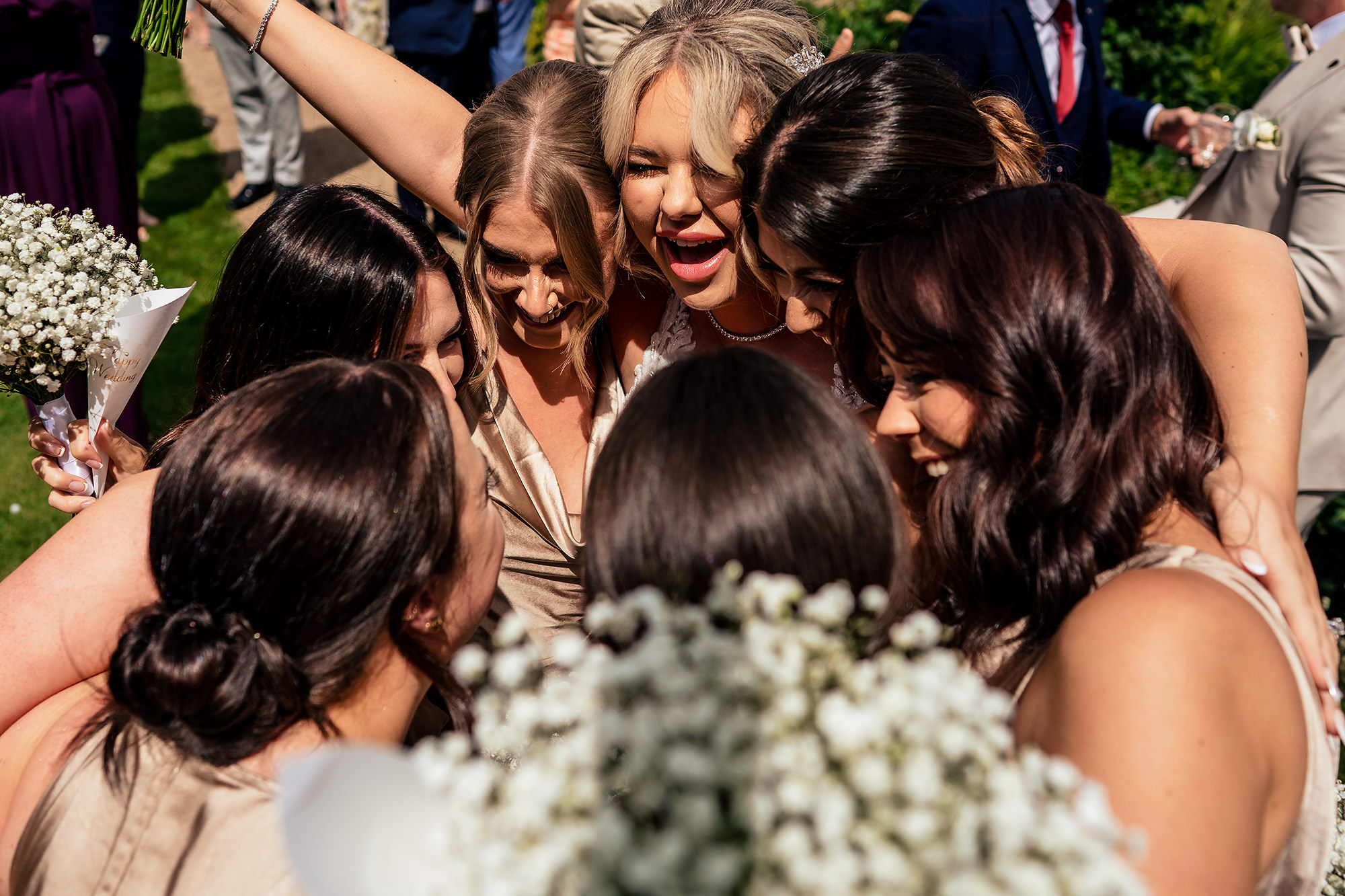 The bridal party in a joyful group huddle after the ceremony at Salt House, Staffordshire