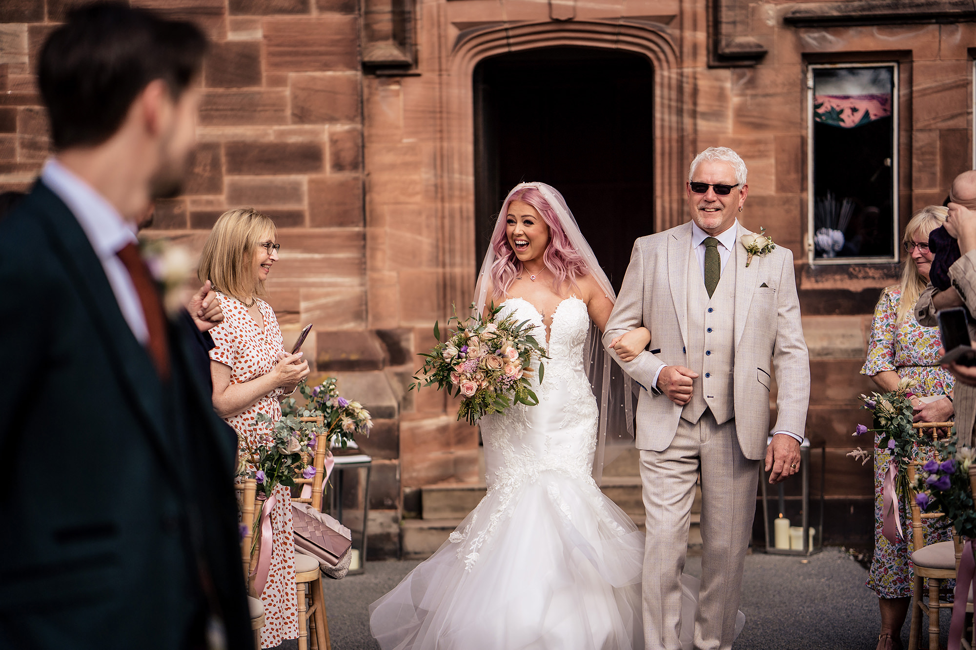 Bride laughing with her dad as they step out for her Standon Hall wedding ceremony