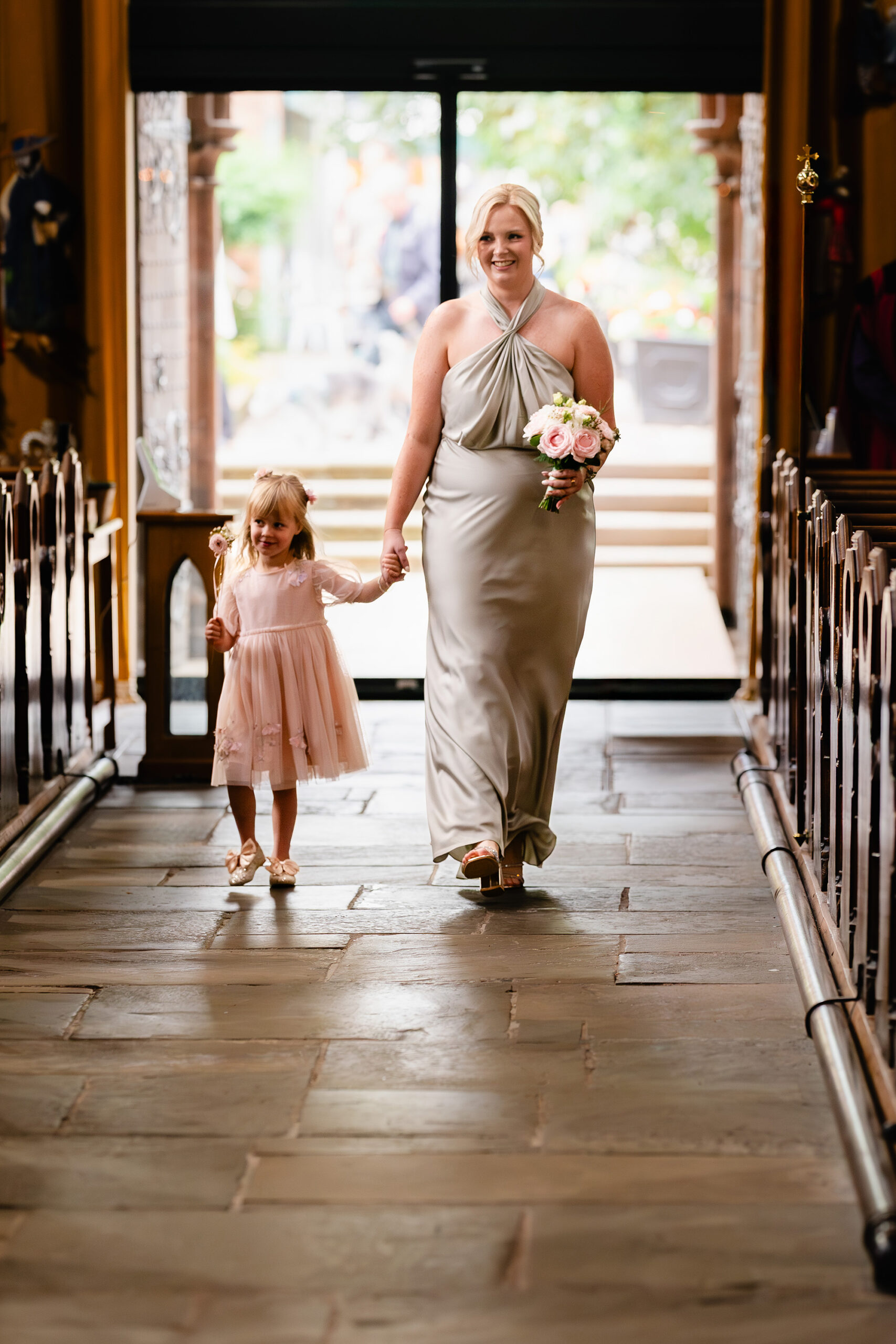 The flower girl and a bridesmaid walking into St Mary’s Church hand in hand