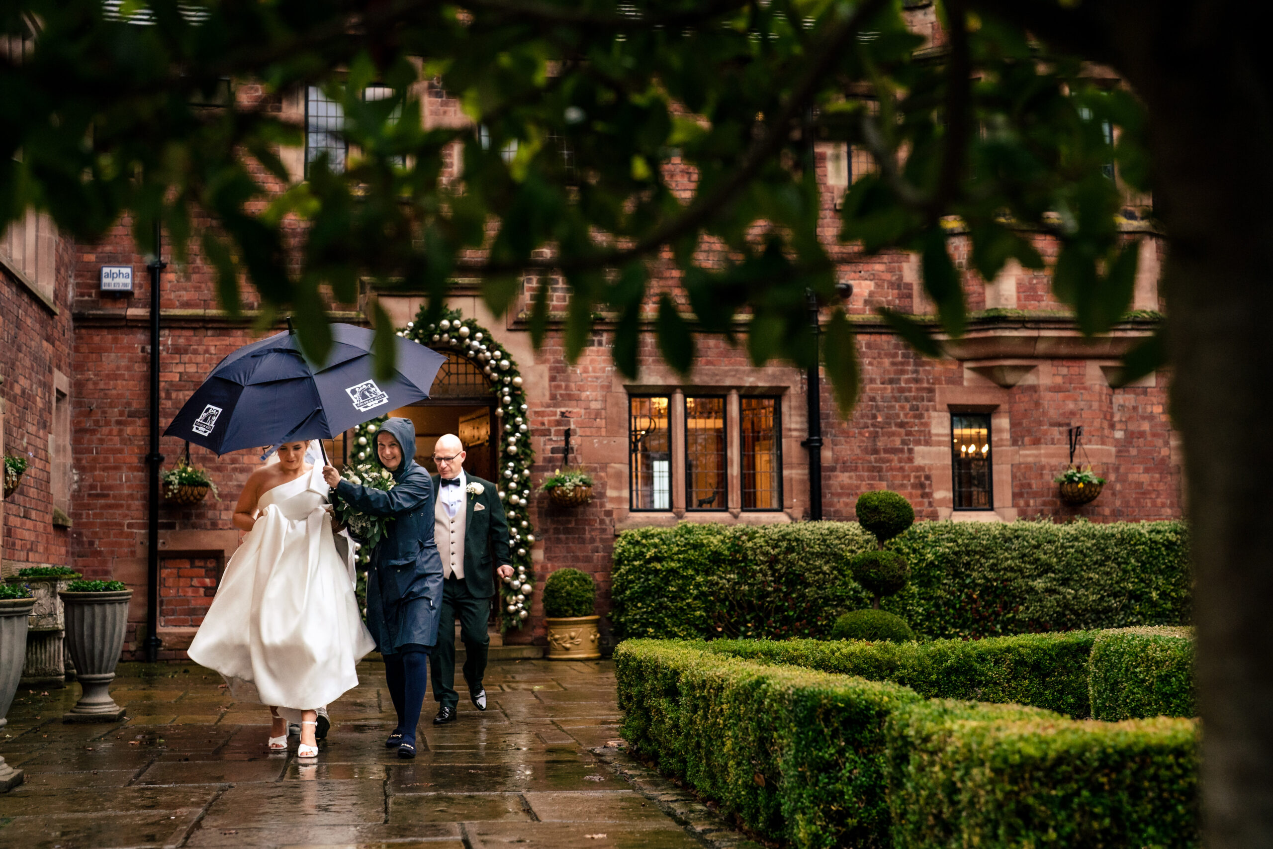Guests making their way to the ceremony under umbrellas at Colshaw Hall