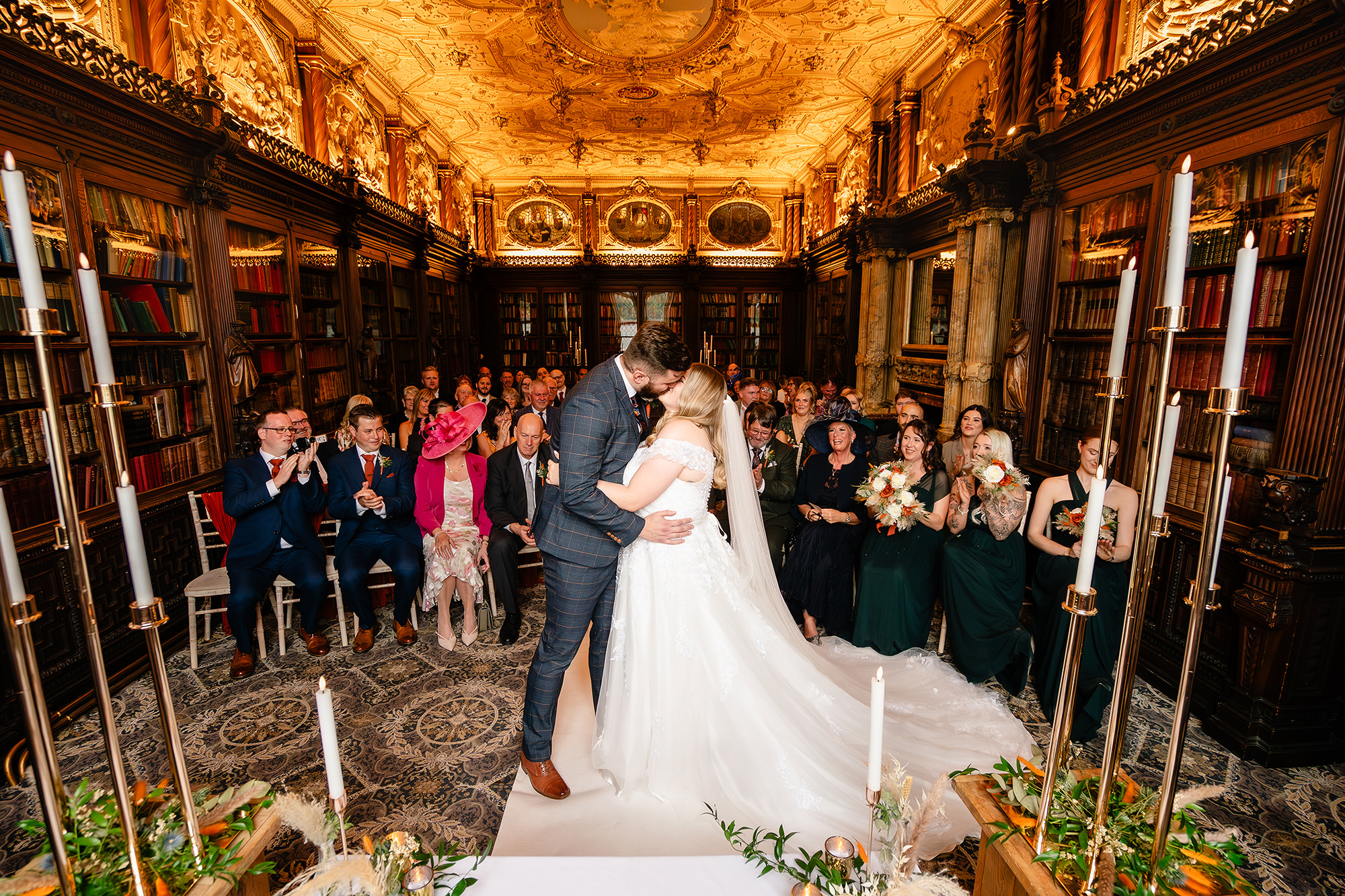 A wide shot of Crewe Hall’s candlelit ceremony room as the newlyweds walk back down the aisle, Cheshire wedding photographer