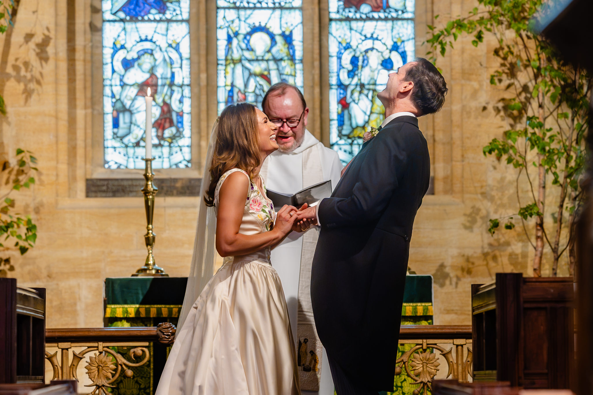Bride and groom saying their vows in front of the stained glass window