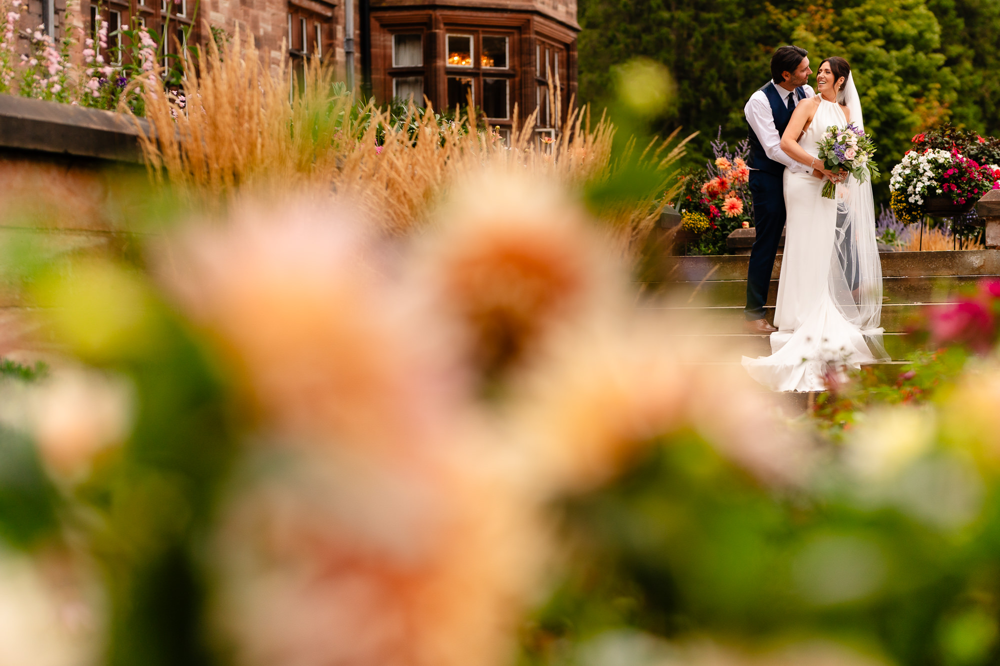 Bride and groom on the stone steps at Salt House surrounded by autumn flowers, Staffordshire wedding photographer
