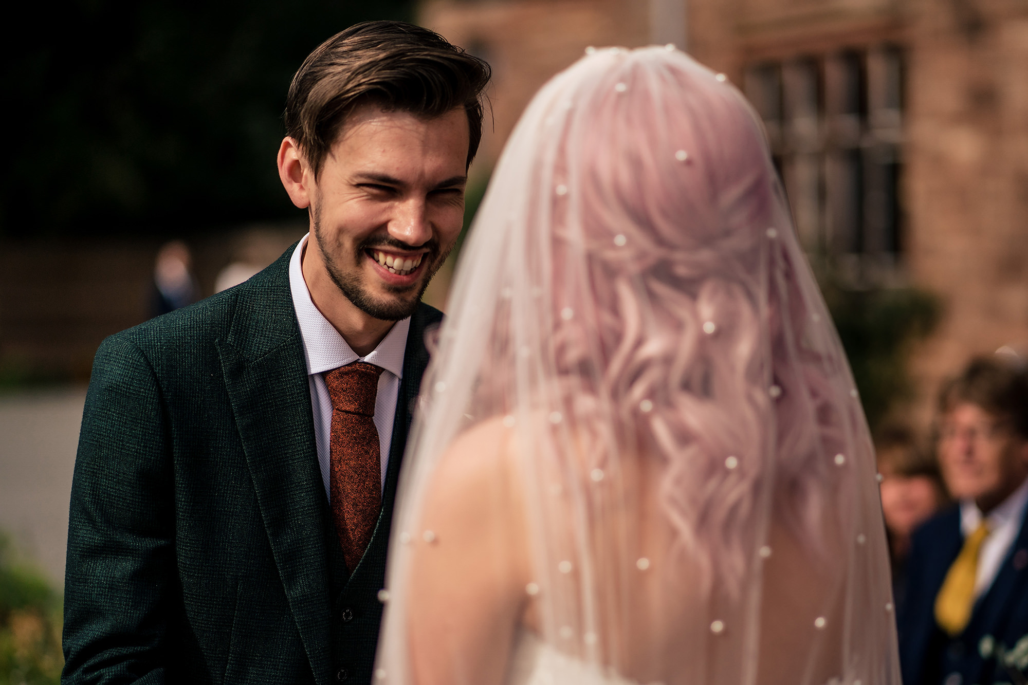 Groom smiling as he sees his bride arrive at their Standon Hall wedding ceremony