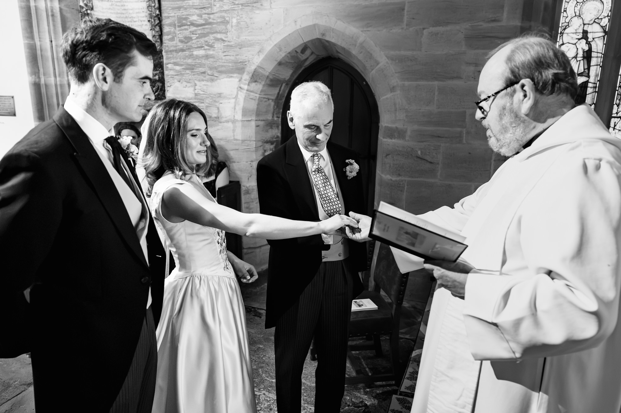 Black and white photograph of the couple signing the register with the vicar