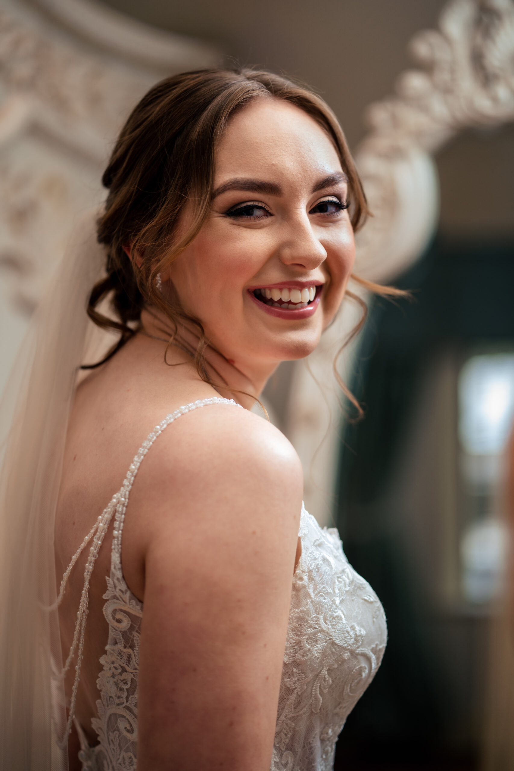 Portrait of Bethany in her veil looking over her shoulder, beaded straps across her back