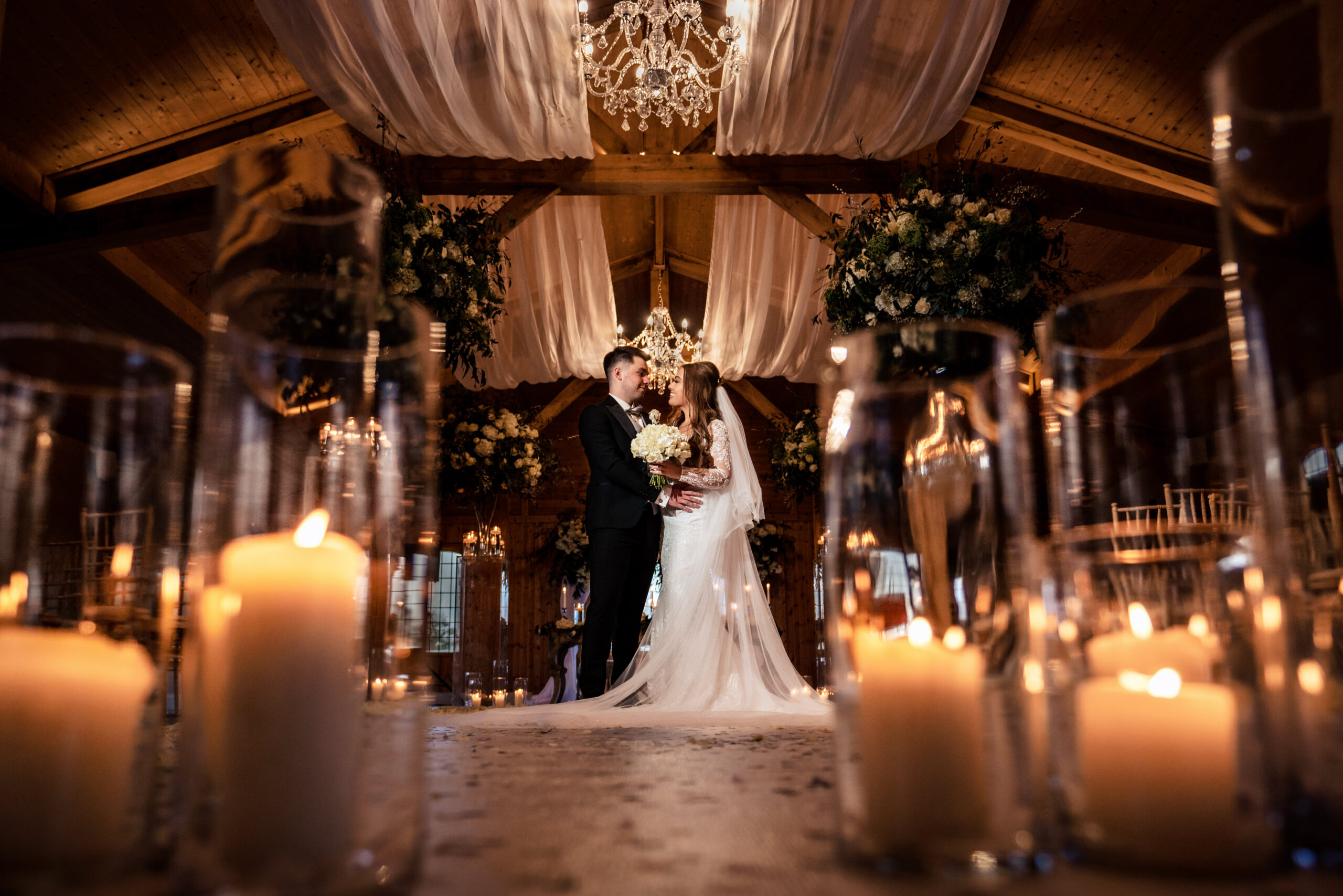 Abbie and Jamie together at the front of the ceremony room framed by candles, Merrydale Manor wedding photographer