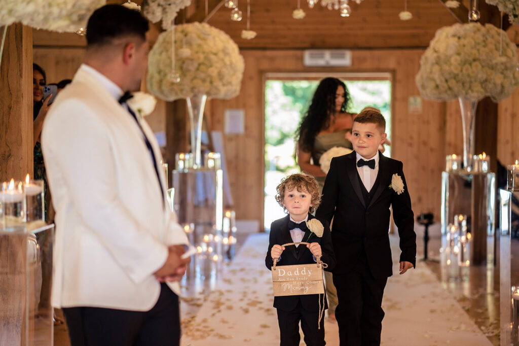 Page boys walking down the aisle with a Daddy are you ready, here comes Mummy sign as Tyrone waits, Merrydale Manor wedding photographer