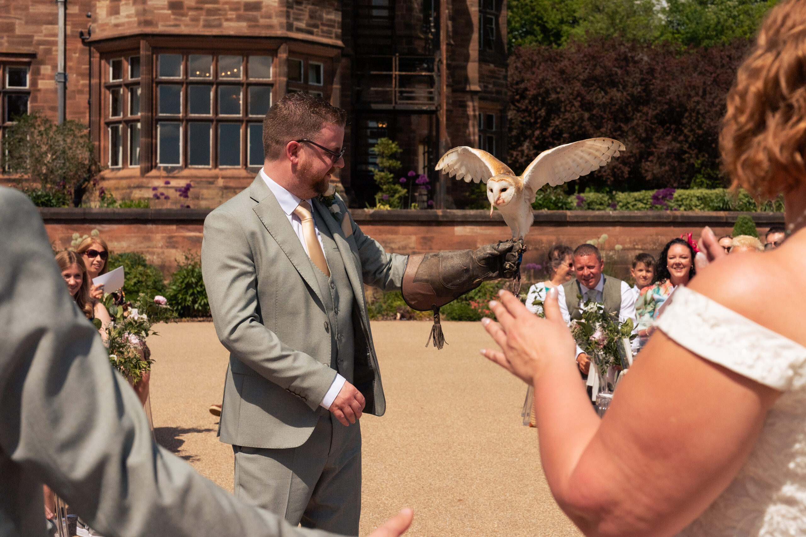 Close up of the barn owl landing on the groom’s glove with the wedding rings during the ceremony