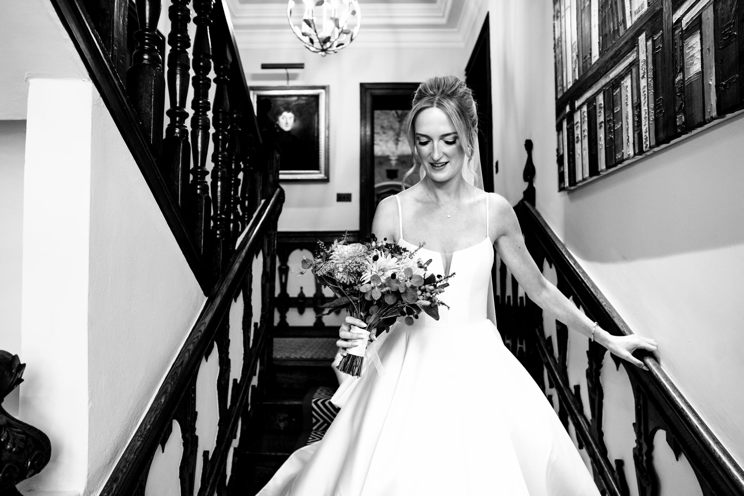 Black and white photograph of the bride coming down the staircase at Dorfold Hall