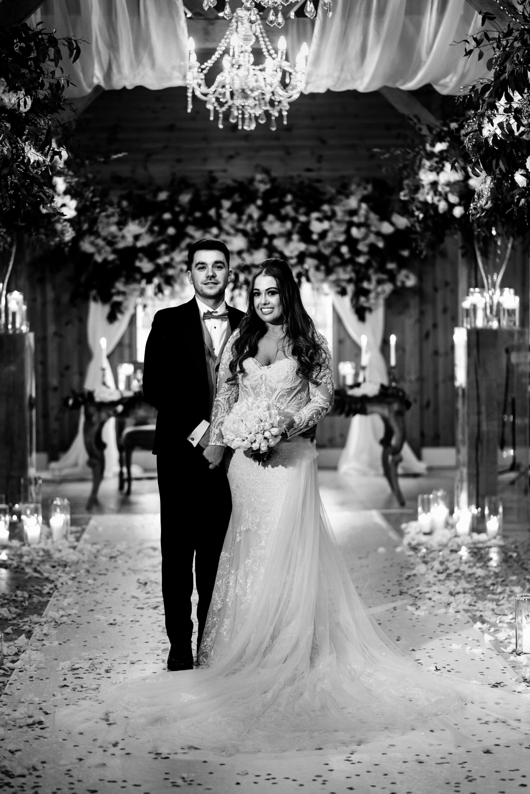 Black and white portrait of Abbie and Jamie under the floral canopy in the ceremony room at Merrydale Manor