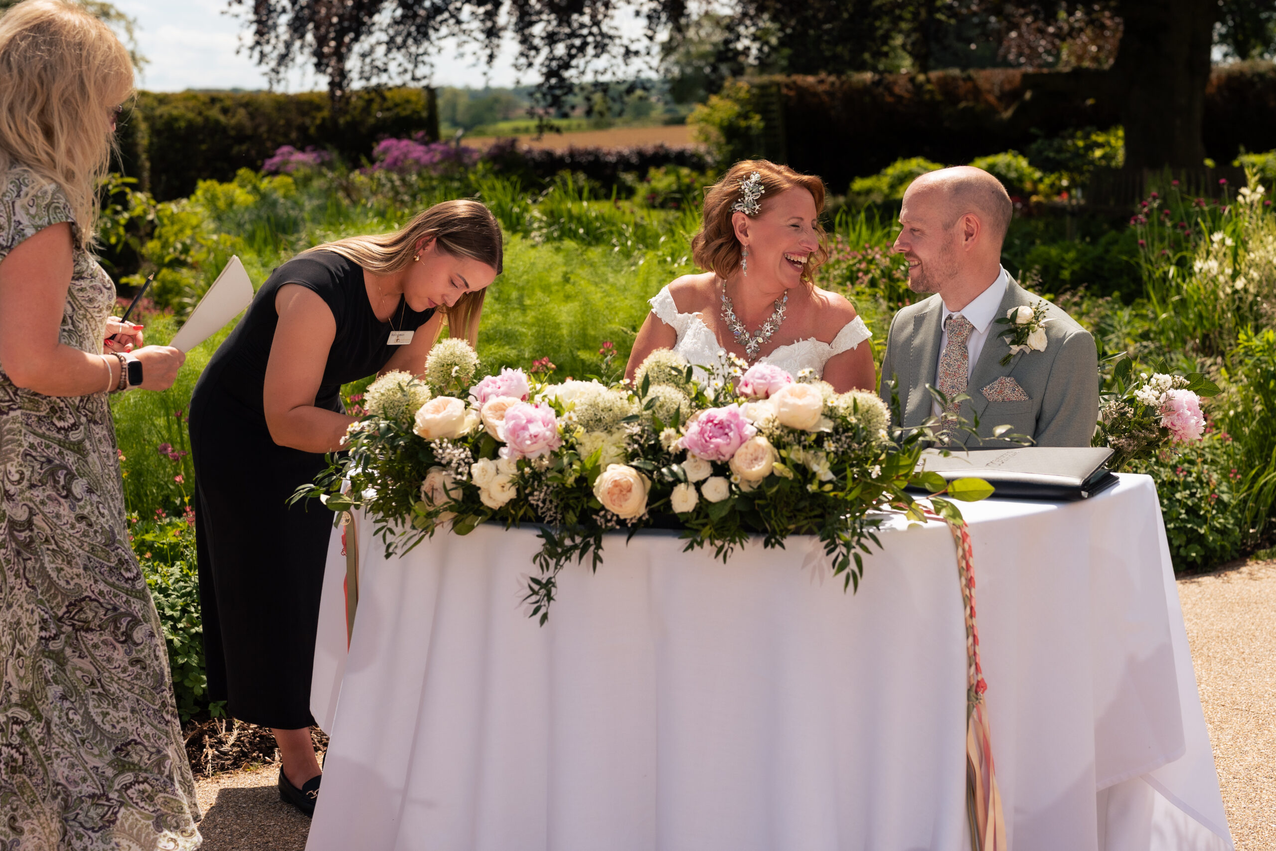Bride and groom signing the register together at Salt House, watched by the registrar