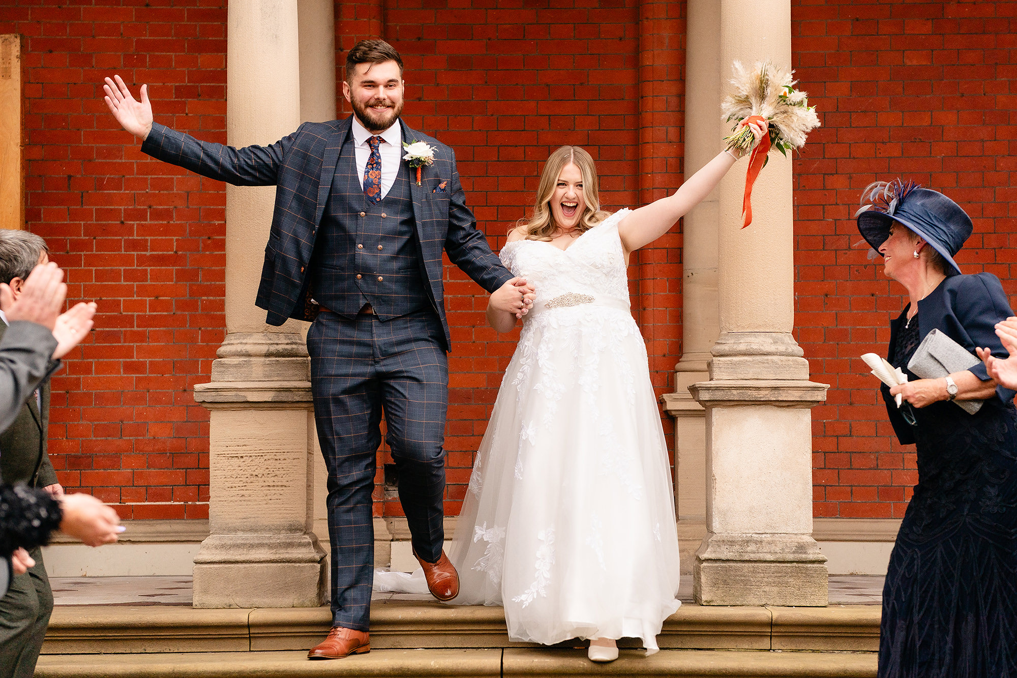 Confetti thrown over Annie and Tom as they step out between Crewe Hall’s brick columns, Cheshire wedding photographer