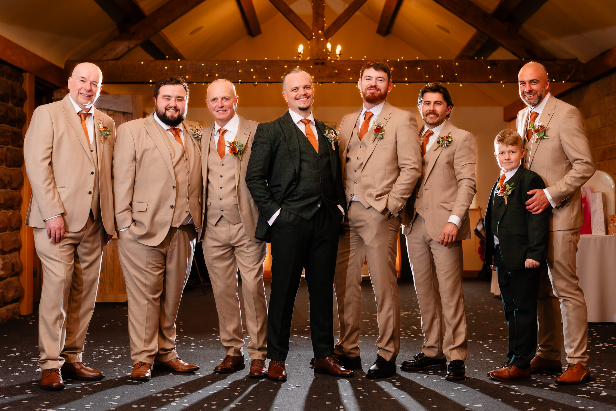 Groom in a dark green suit with his groomsmen in tan suits and orange ties, Heaton House Farm wedding