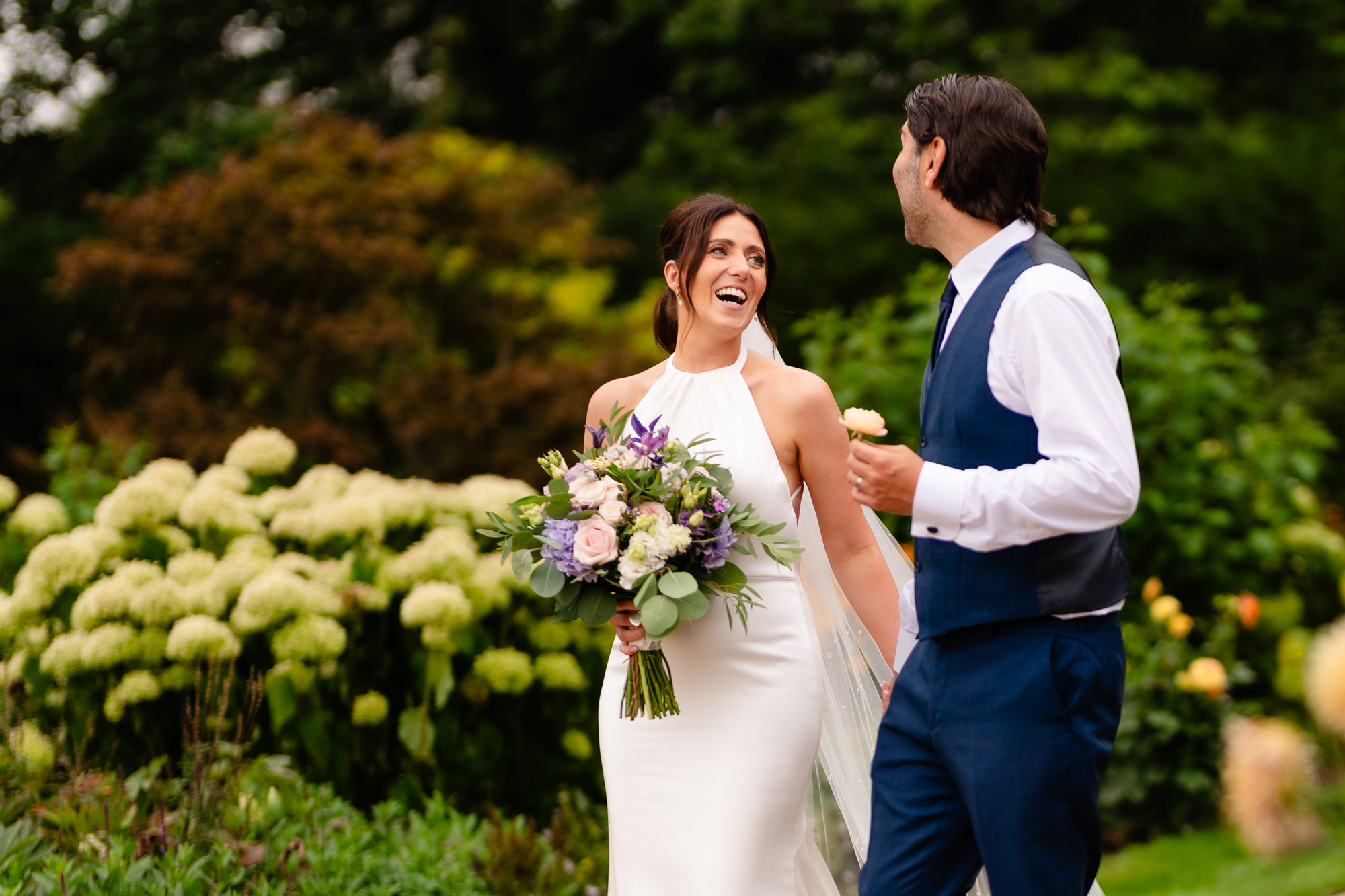 Bride laughing while walking with her groom through the gardens at Salt House, Staffordshire wedding photographer