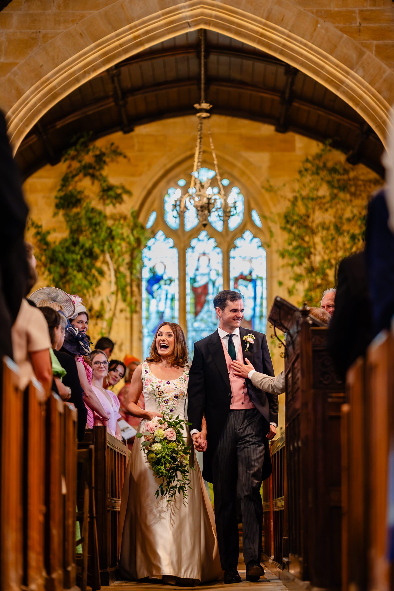 Bride and groom leaving the church framed by the stone arch, Dorset wedding photographer