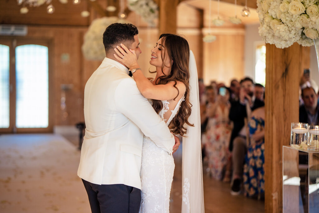 Gemma holding Tyrone’s face as they embrace at the front of the ceremony room, guests watching