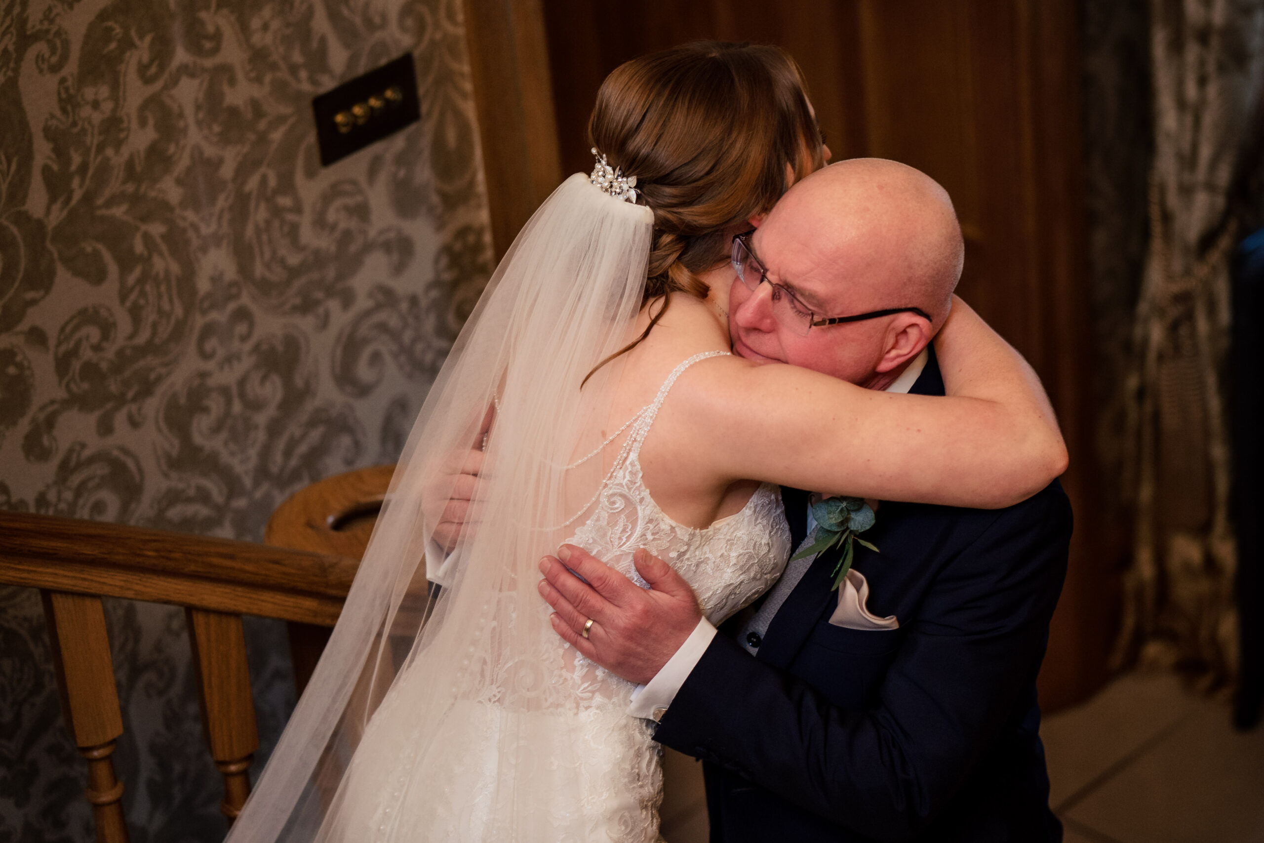 Bethany hugging her dad at the bottom of the stairs during the first look