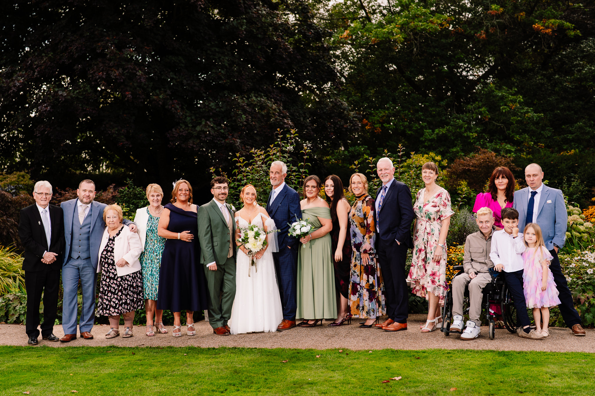 A large family group photo with the bride and groom in the gardens at Salt House