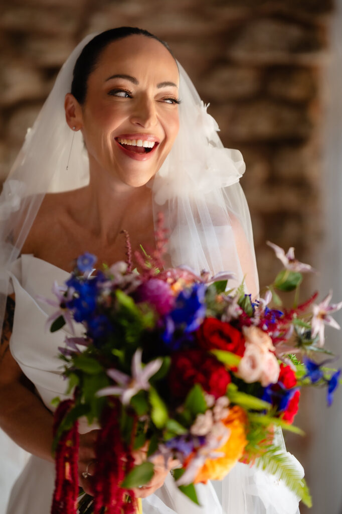 Kim laughing in her veil holding her bright bouquet, Swancar Farm Country House, Nottingham wedding photographer