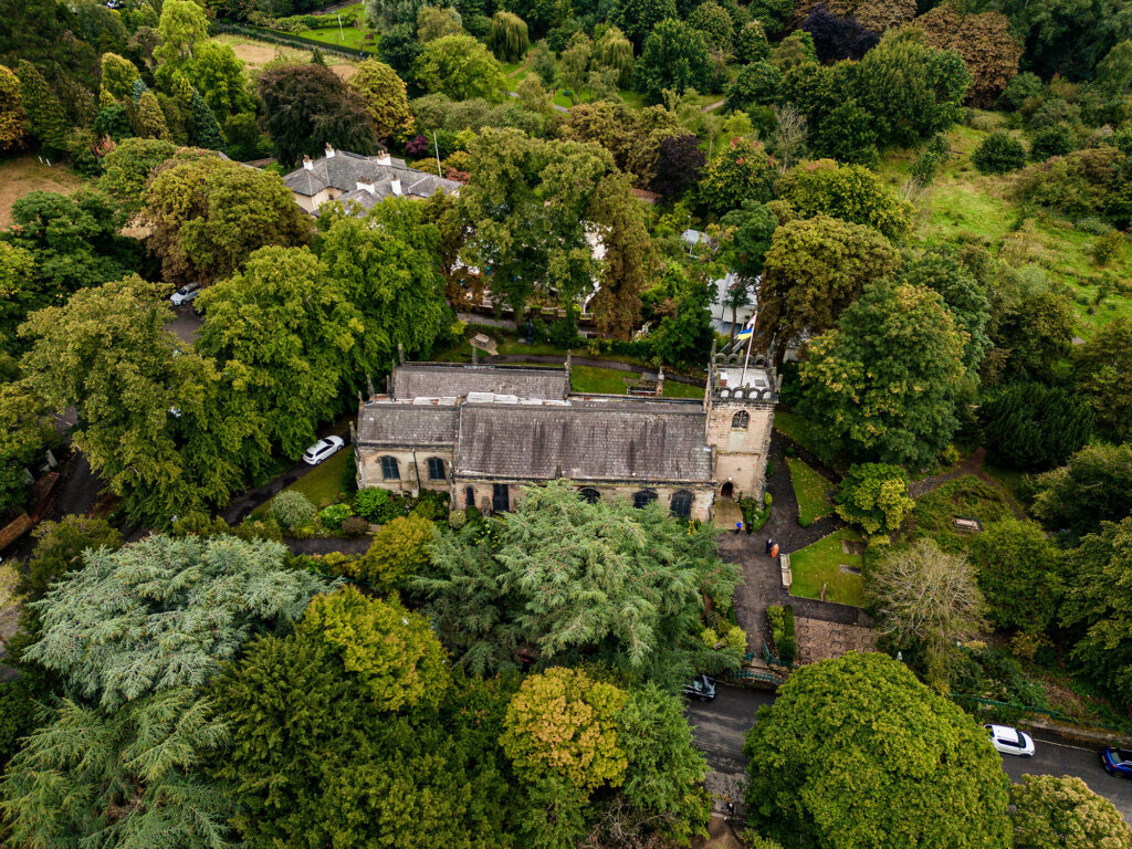 Aerial drone view of St James Church in Didsbury surrounded by trees, Cheshire wedding photographer
