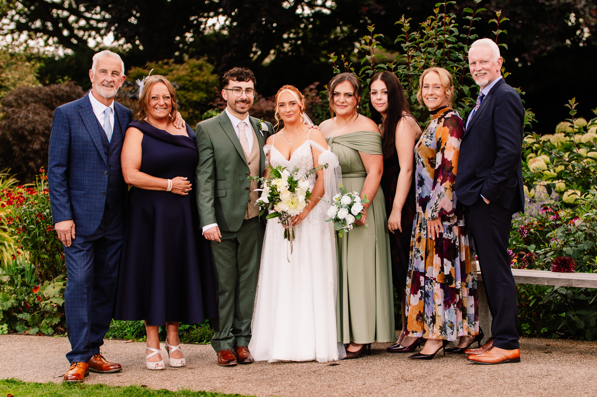 Bride and groom with family members smiling together for a formal photo