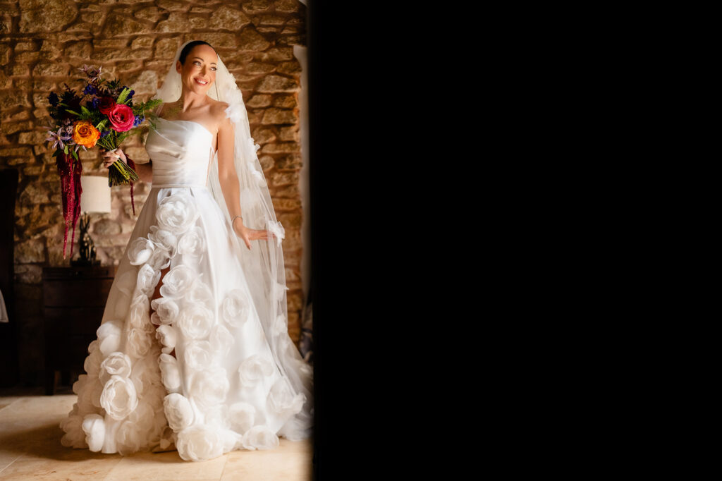 Kim standing in a doorway in her dress, veil and bouquet with deep shadow beside her, Swancar Farm wedding photographer