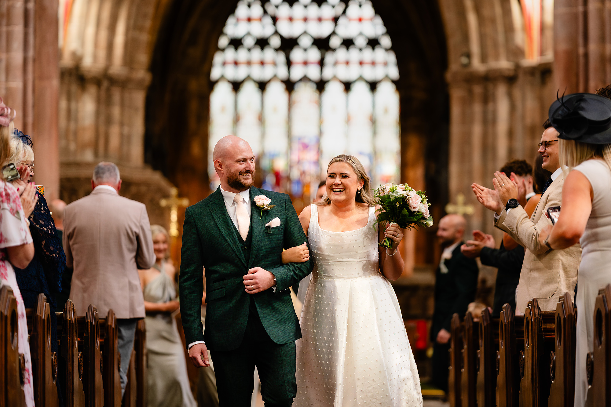 Chloe and Pete walking down the aisle, backlit by St Mary’s stained glass