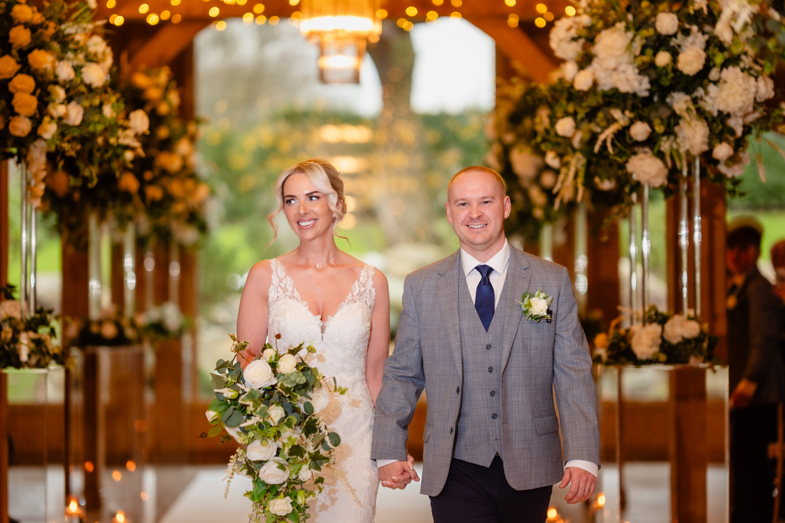 Bride and groom walking back up the aisle hand in hand under the floral installations, Colshaw Hall Cheshire wedding photographer