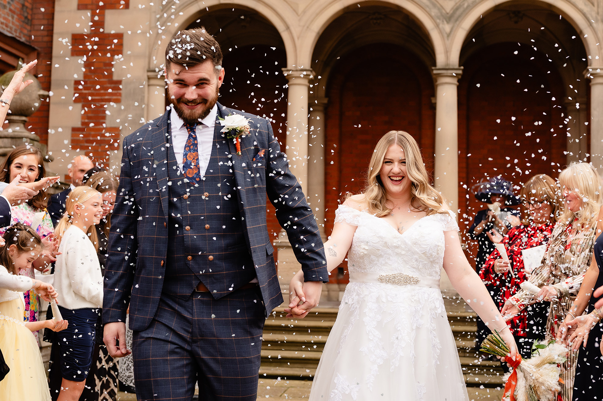 Confetti showering down as the newlyweds laugh together, Crewe Hall wedding photographer