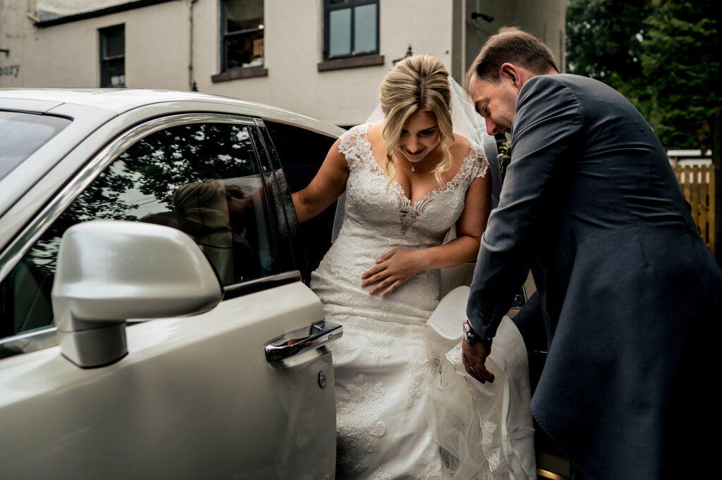 Bride stepping out of a white Rolls-Royce at St James Church Didsbury, Merrydale Manor wedding photographer