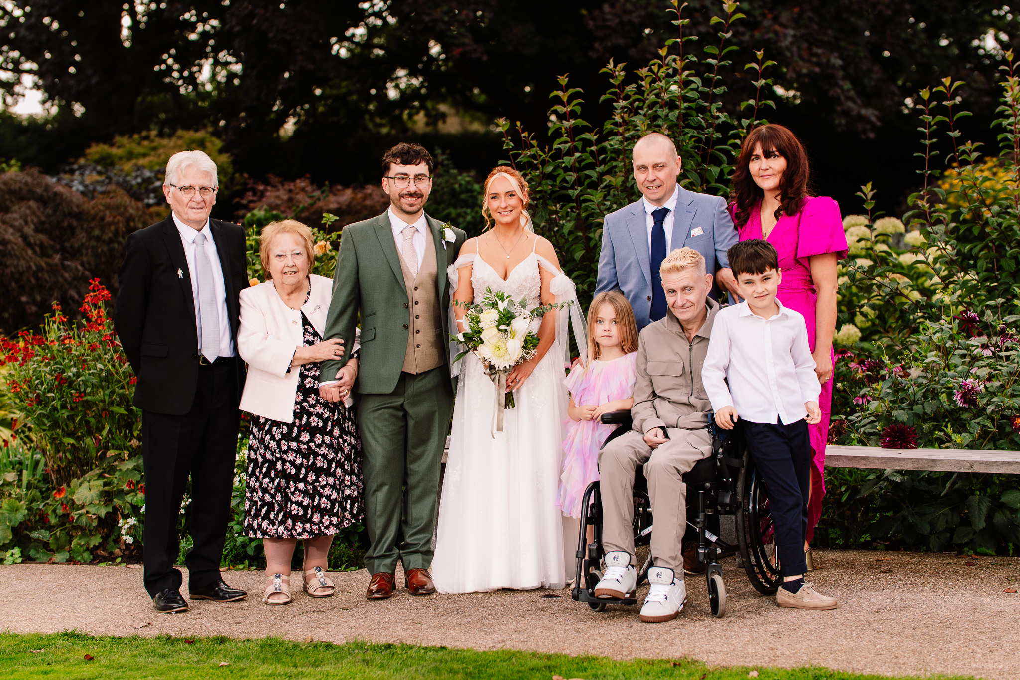 Family formal photo of the bride and groom with family members in the gardens at Salt House