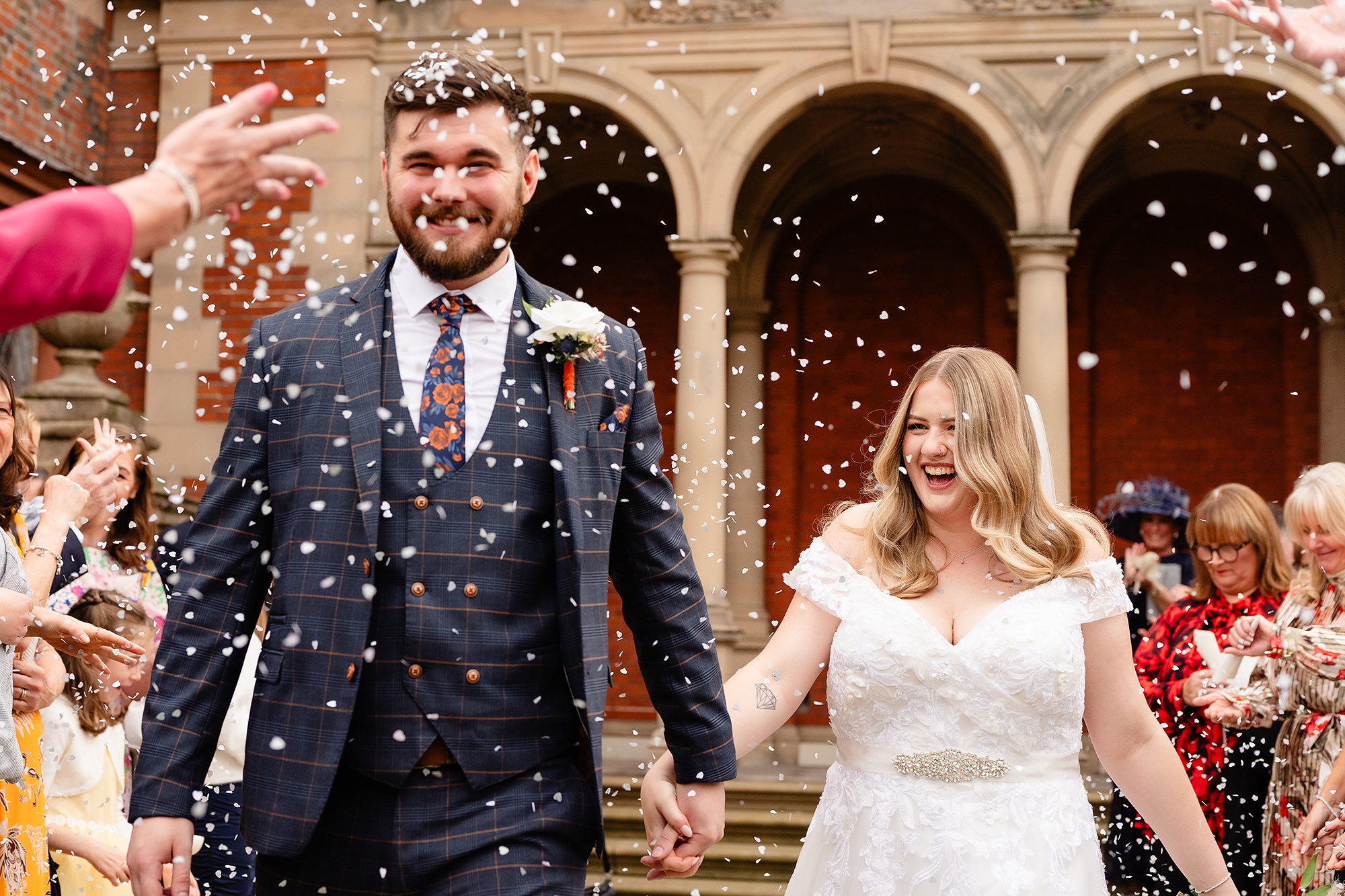 The groom laughing as confetti covers his face outside Crewe Hall, Cheshire wedding photographer