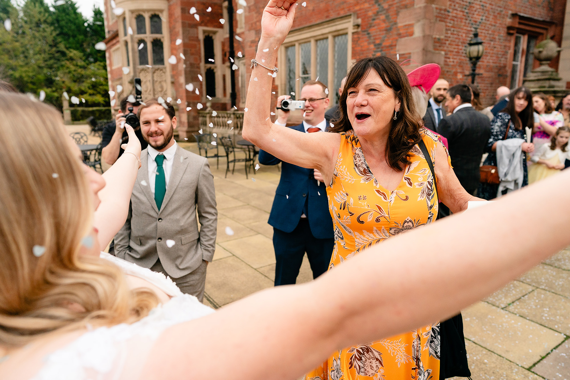 A guest celebrating and throwing confetti during the exit at Crewe Hall, Cheshire wedding photographer
