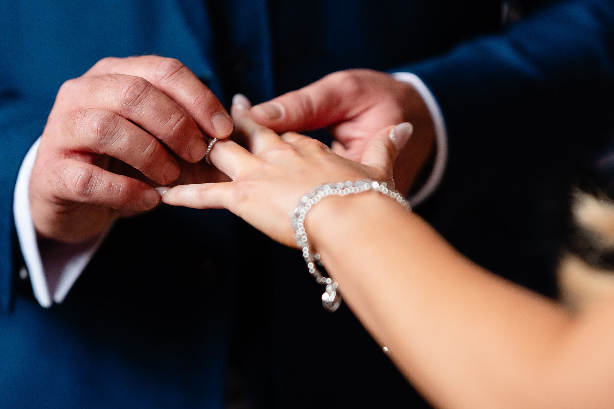 Close up of the wedding ring going onto the bride’s finger, a crystal bracelet at her wrist