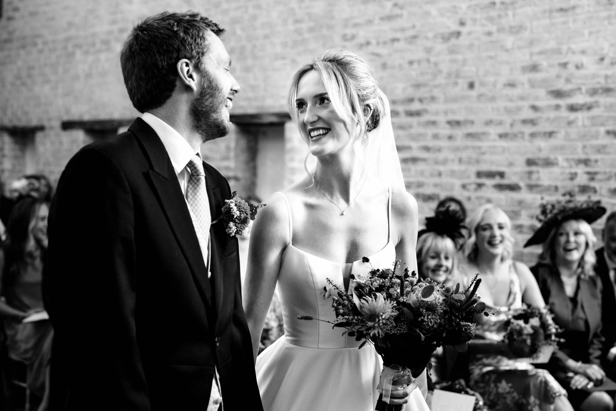 Black and white photograph of the couple grinning at each other at the top of the aisle, Cheshire wedding photographer