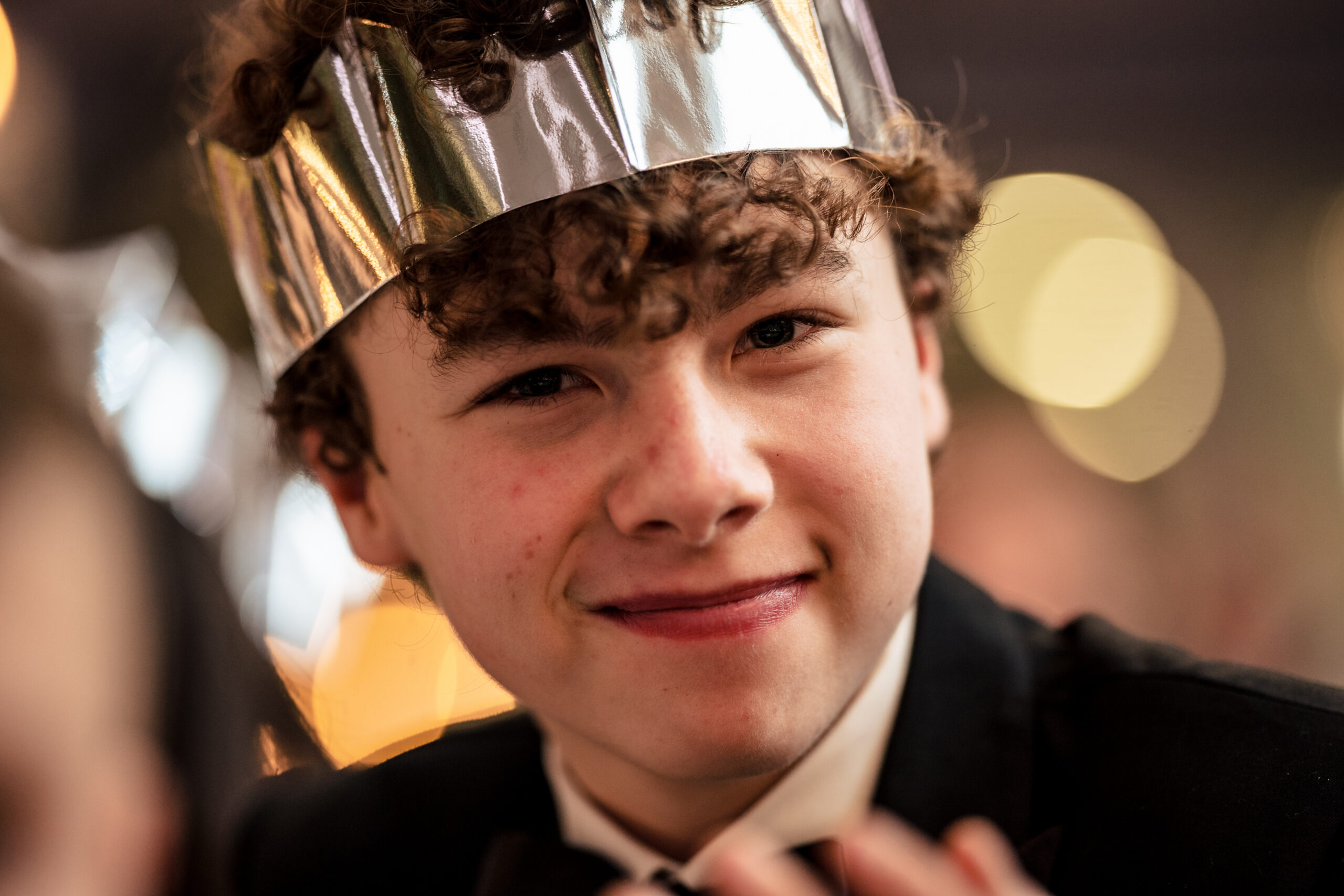 A young guest grinning in a silver paper crown at the tables, Cheshire wedding photographer