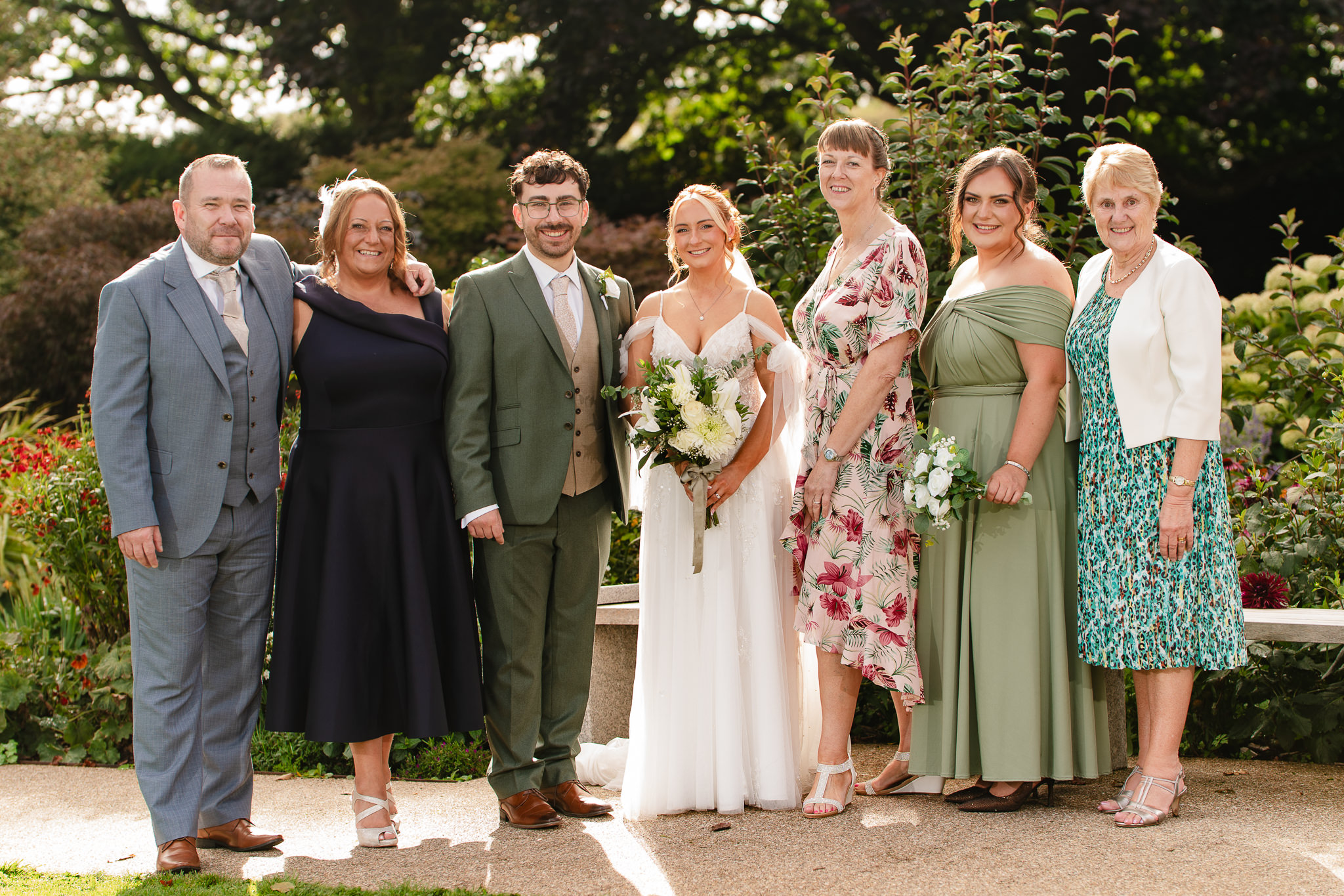 Family formal group photo with the newlyweds smiling in the sunshine
