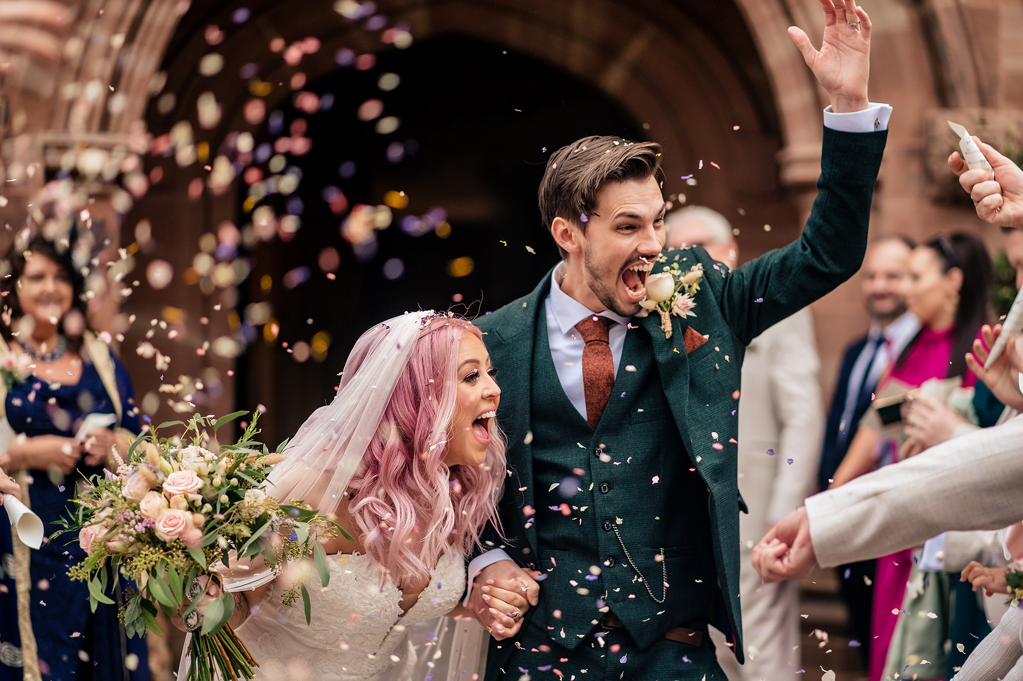 Close up of the newlyweds mid laugh as guests throw confetti at Standon Hall