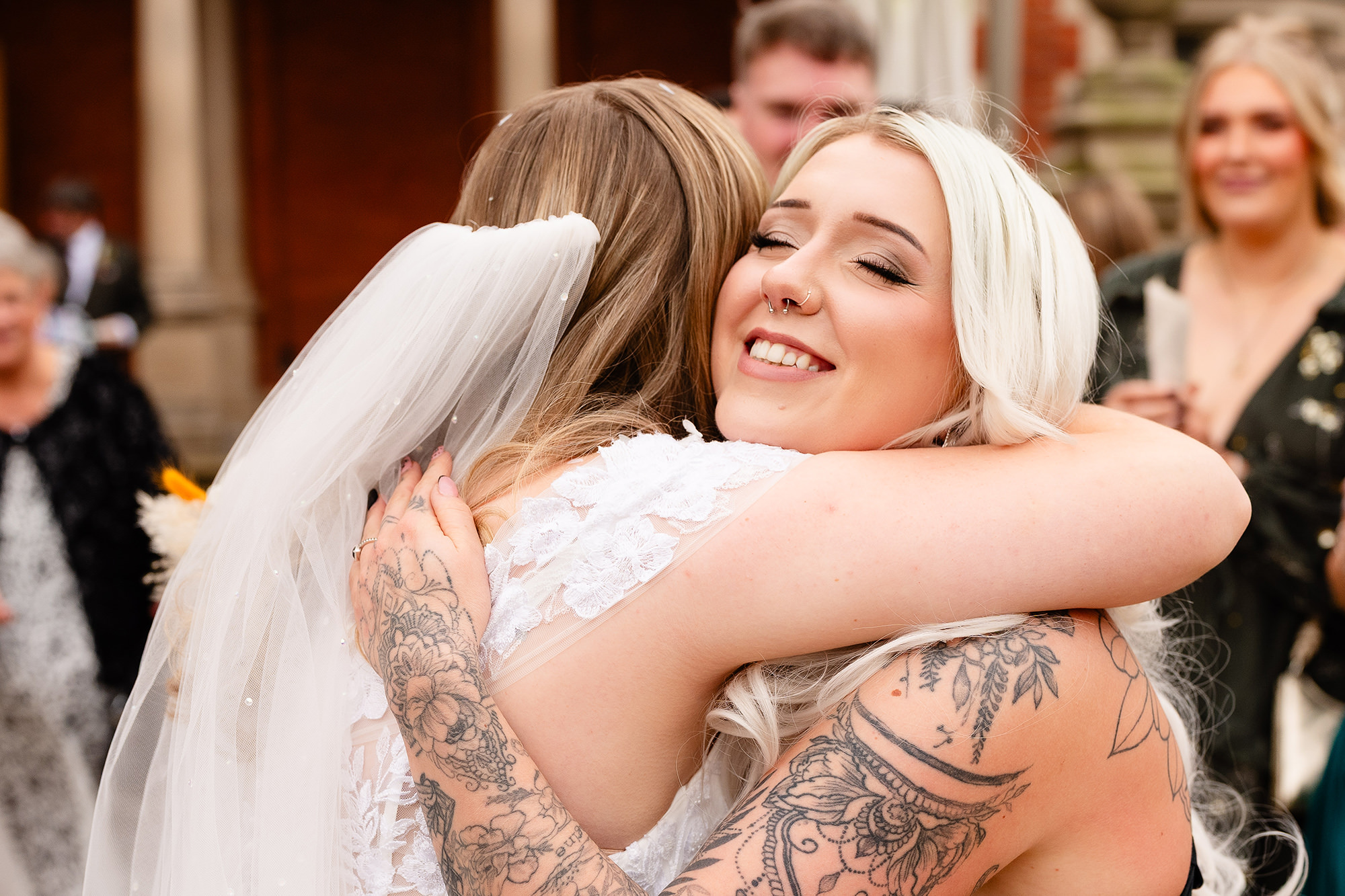 The bride hugging one of her bridesmaids after the confetti exit, Crewe Hall wedding photographer