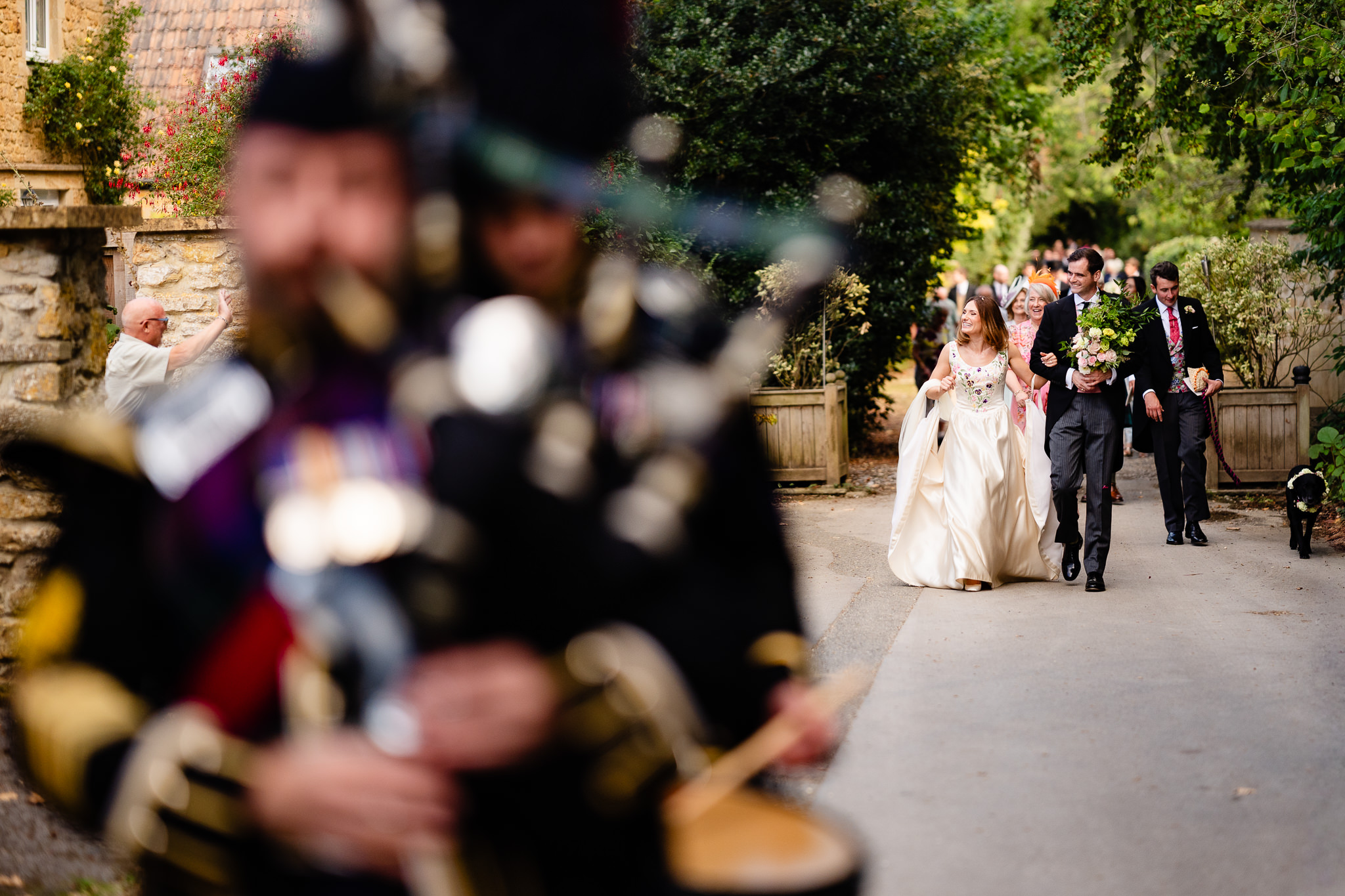 Bride and groom walking back to the reception behind the pipe band, Dorset marquee wedding photographer