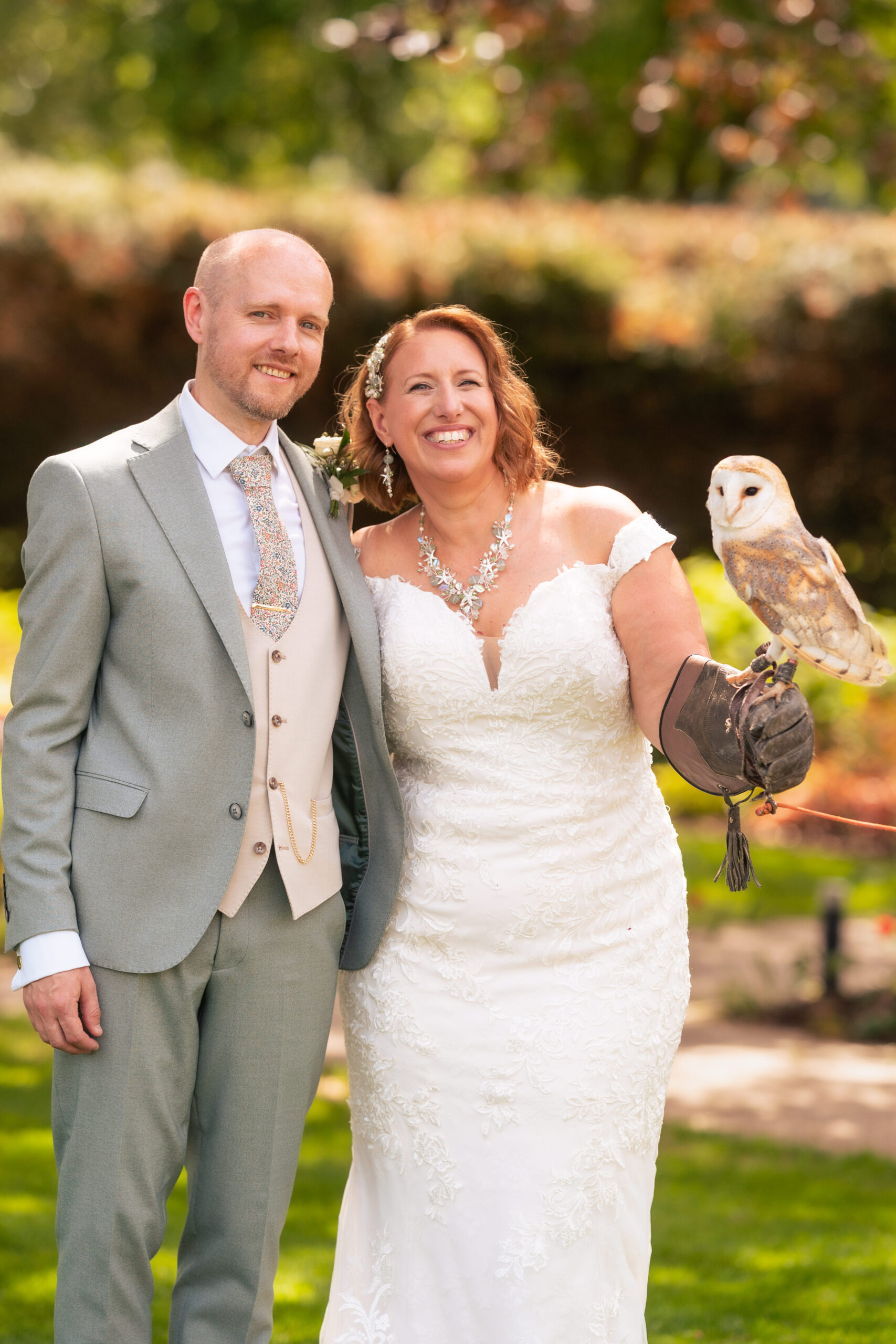 Bride and groom smiling together with the barn owl on the groom’s glove in the Salt House gardens