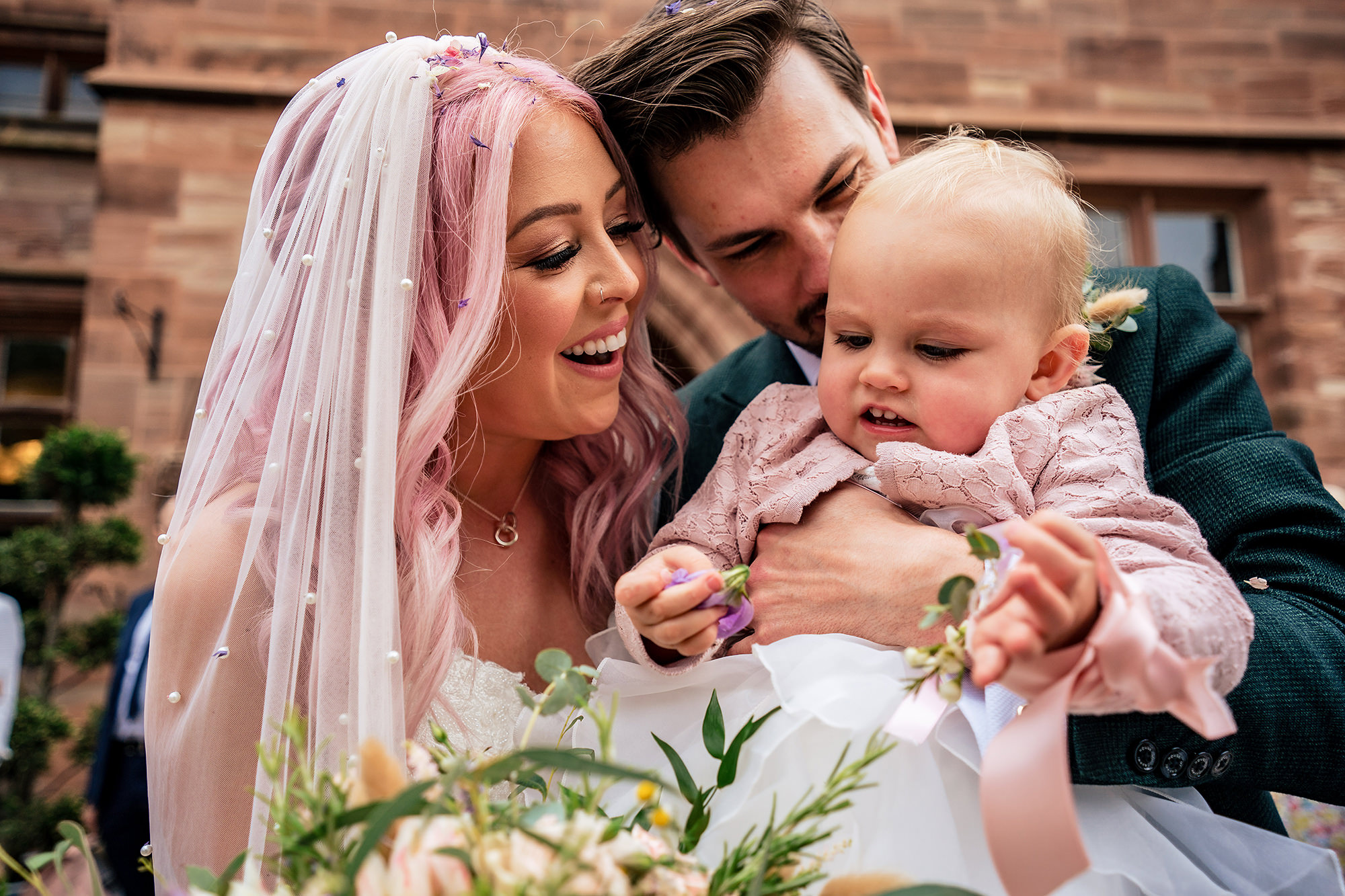 Bride and groom sharing a tender moment with their little girl just after the ceremony at Standon Hall