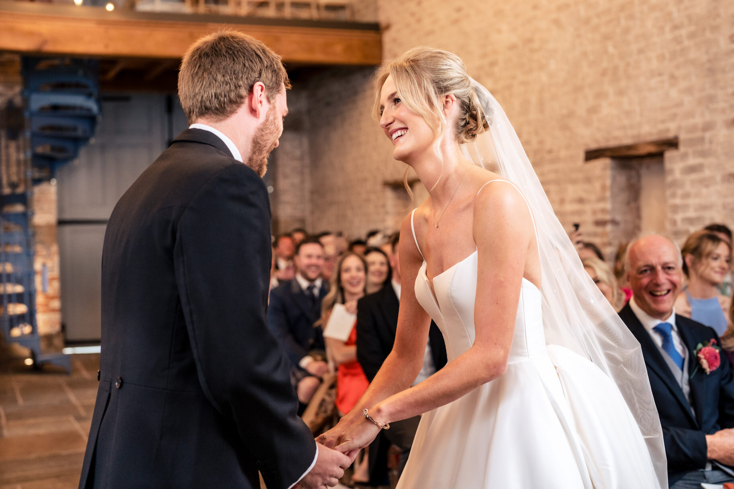 Bride and groom holding hands and laughing as they say their vows, Dorfold Hall wedding photographer