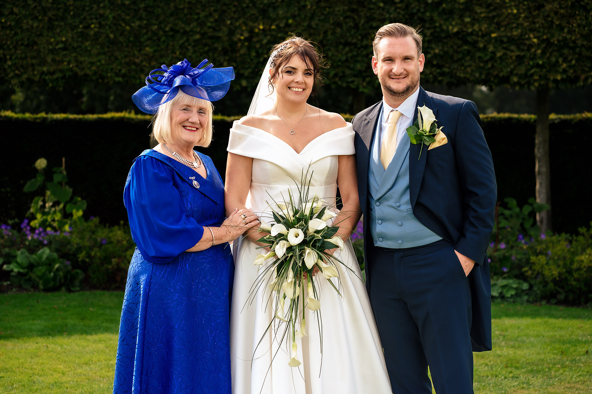 Laura and Ryan posed with a guest at the floral arch, Merrydale Manor wedding photographer