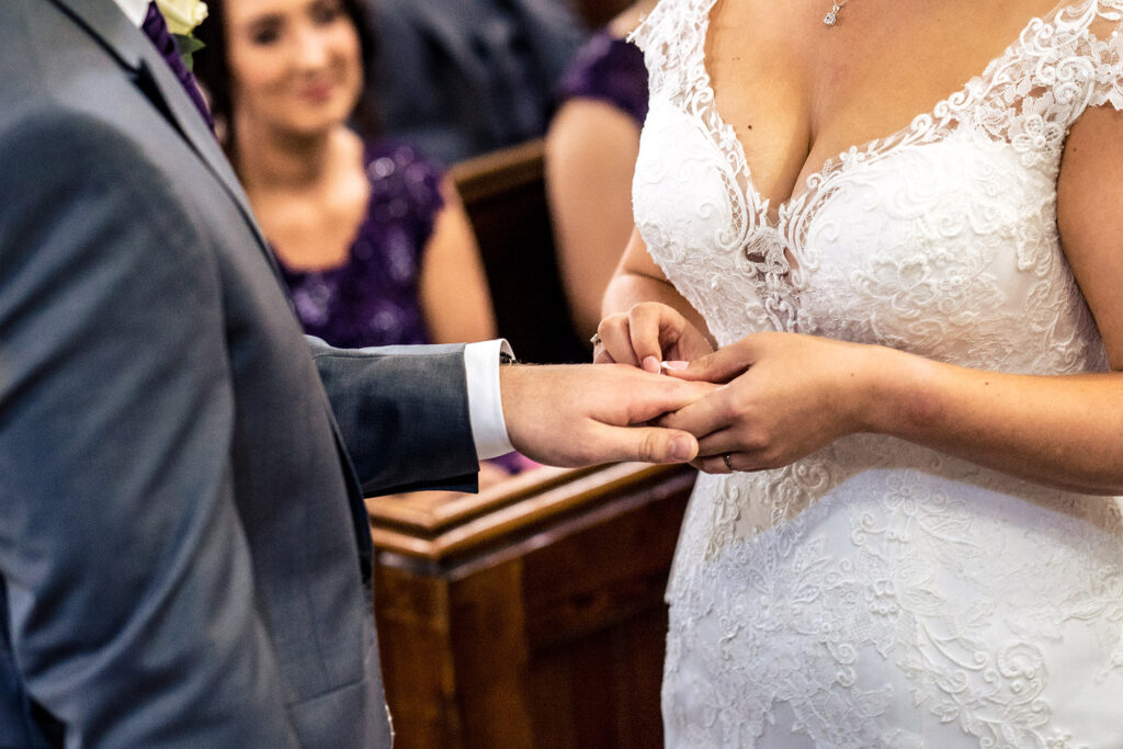 Groom placing the wedding ring on the bride's finger during the church ceremony, Merrydale Manor wedding photographer