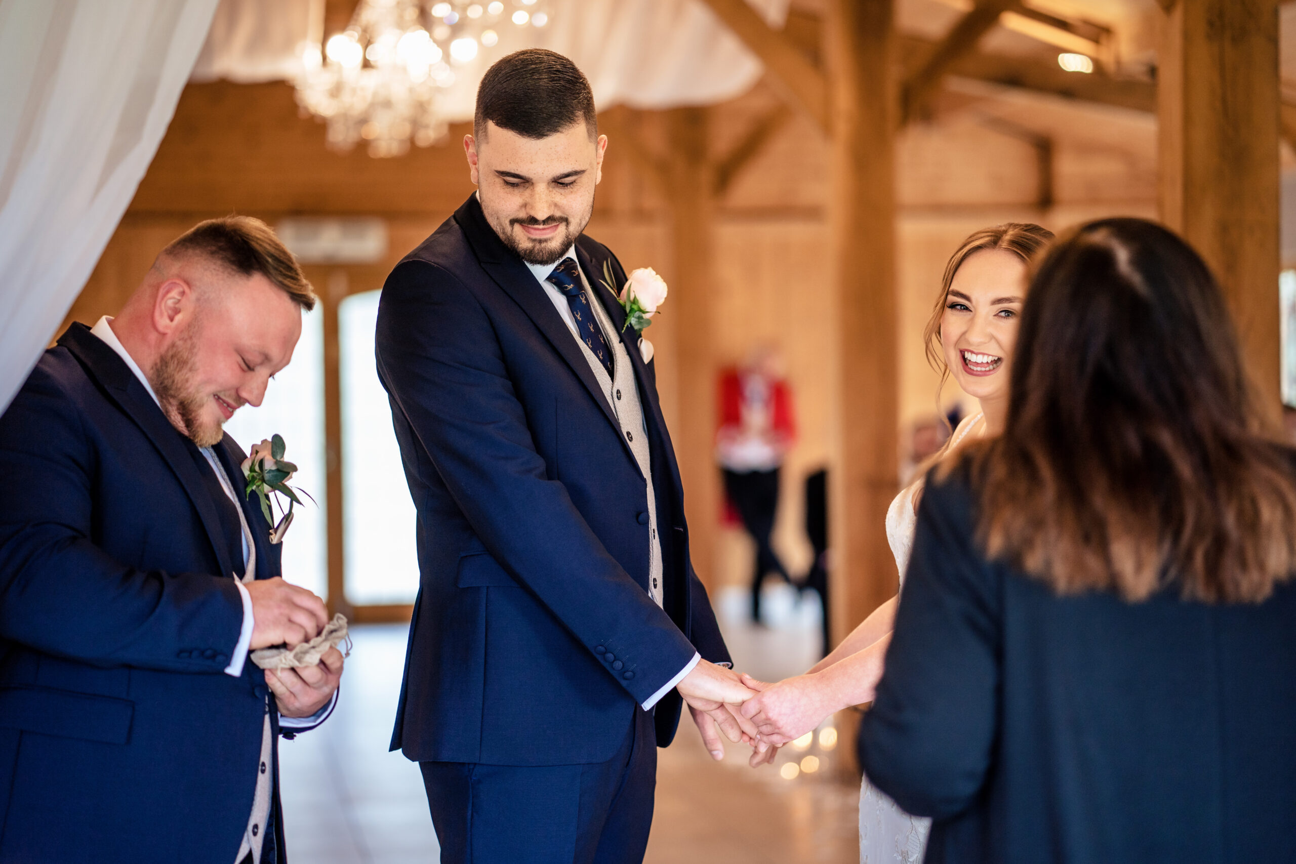 Dean laughing as a groomsman gets the rings ready, with Bethany smiling opposite him