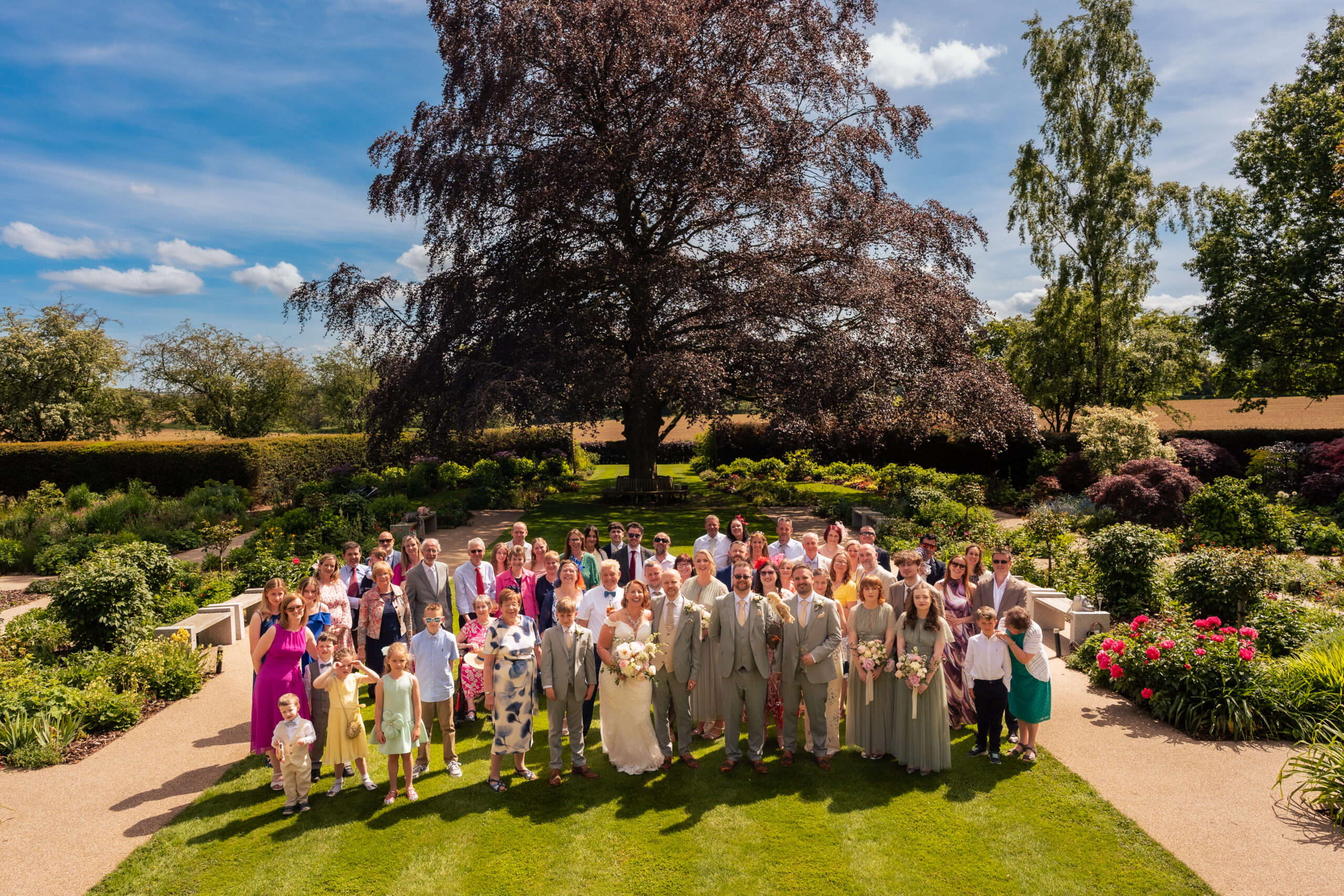 Aerial view of the full wedding party gathered on the lawn at Salt House for a group photograph