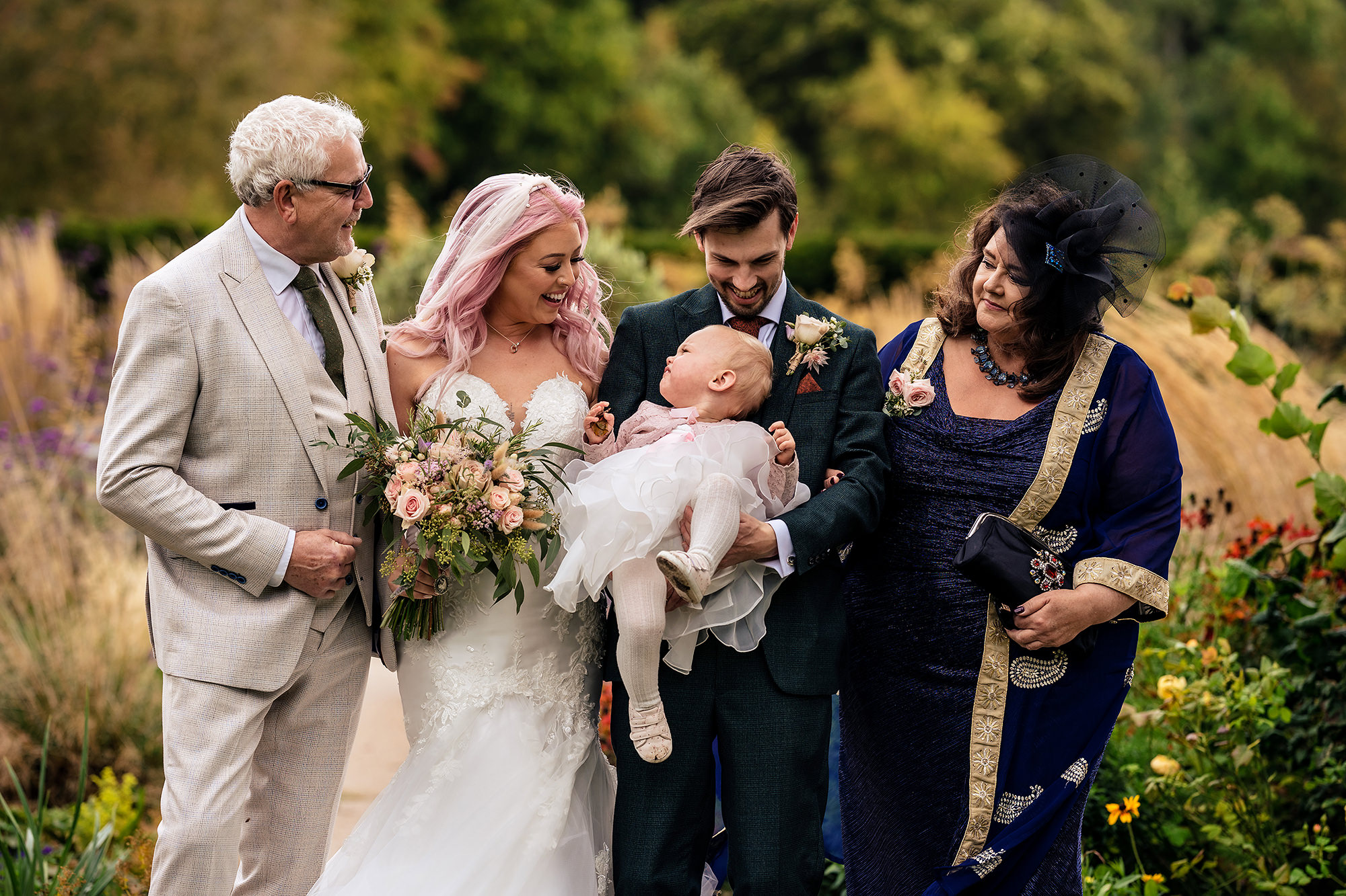 Bride, groom and their families laughing together in the gardens at Standon Hall