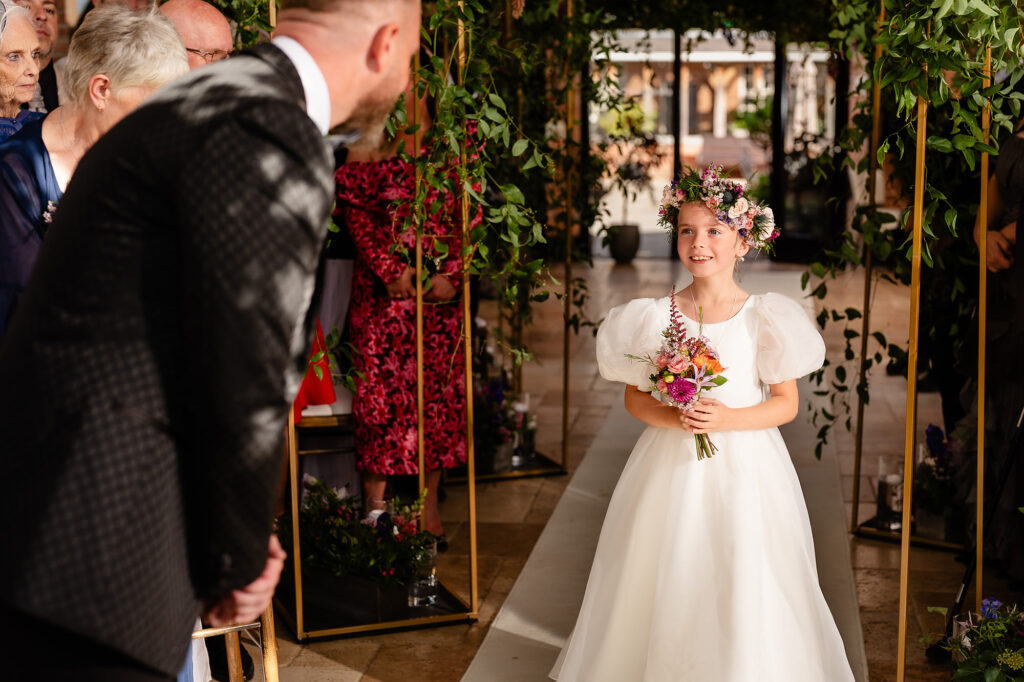 Flower girl in a flower crown walking down the aisle towards Glynn, Swancar Farm wedding photographer